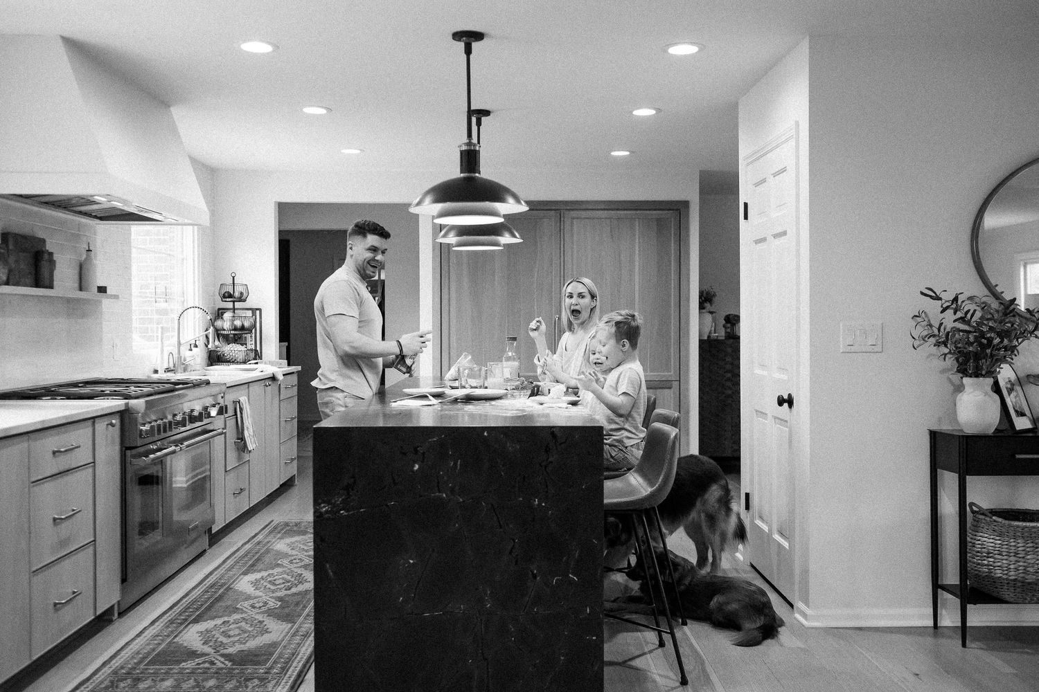 Black and white photo of a family gathered around a large kitchen island in a modern home.