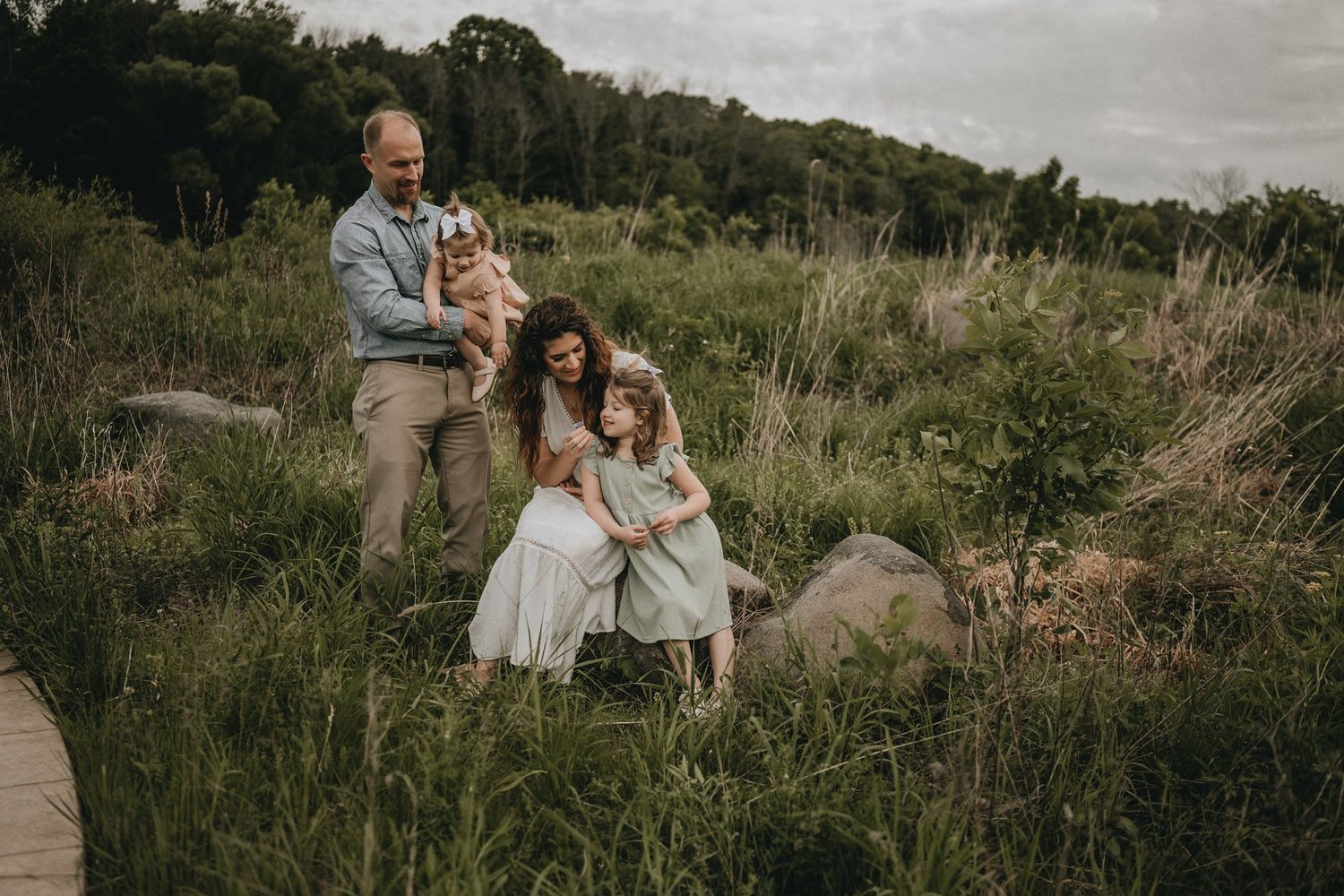 A family poses together among tall grasses beside a winding path.