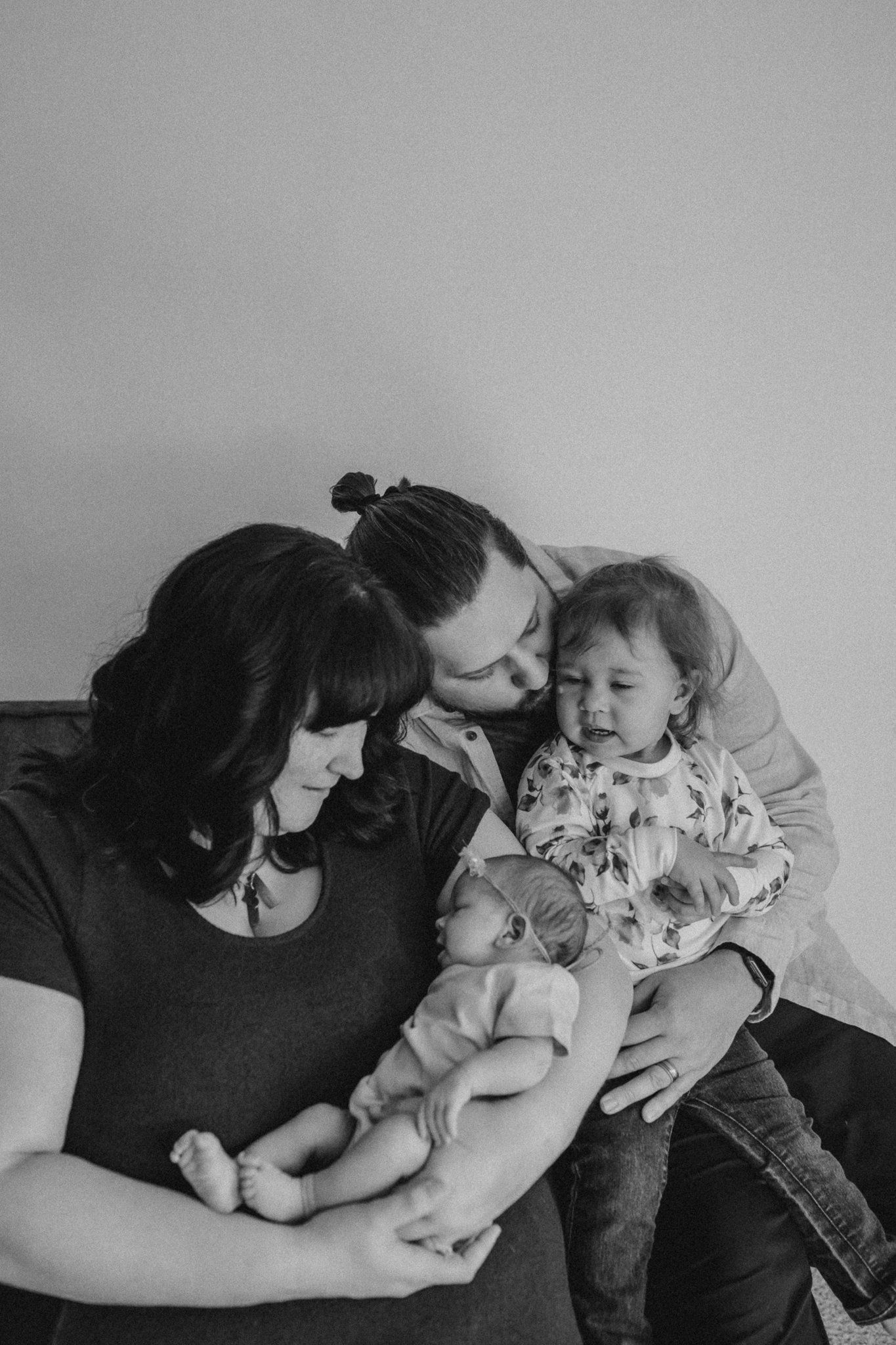 A tender black and white family portrait showing intimate moments on a couch.