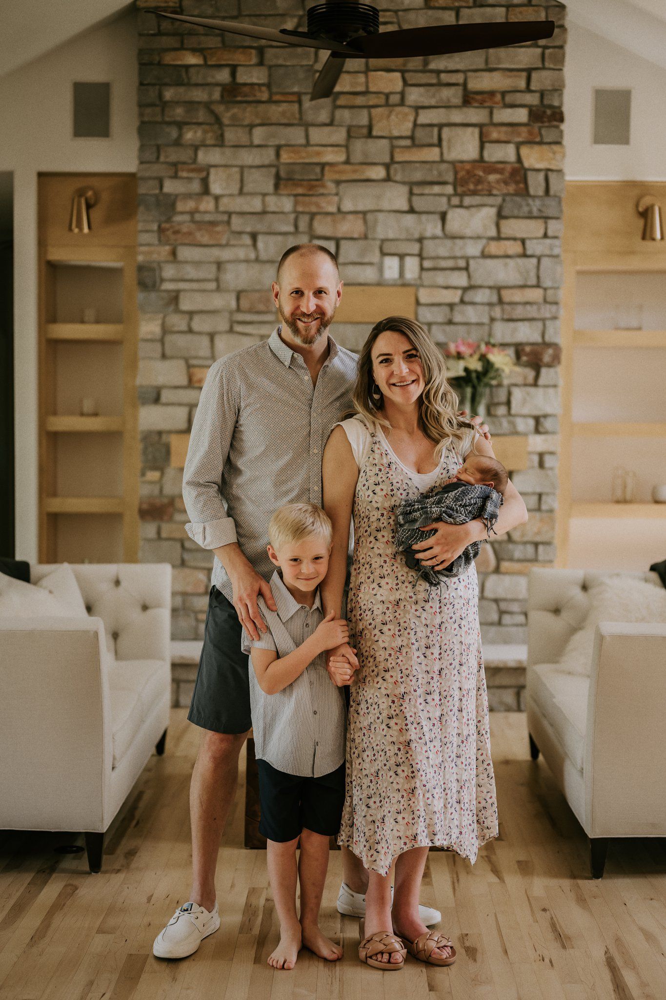 A family standing together in front of a stone fireplace in a modern living room.