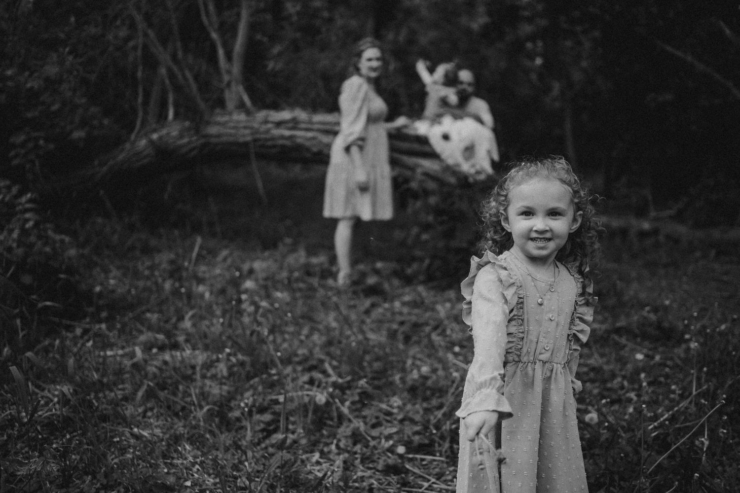 A candid black and white photo capturing a sweet moment in a forest setting.
