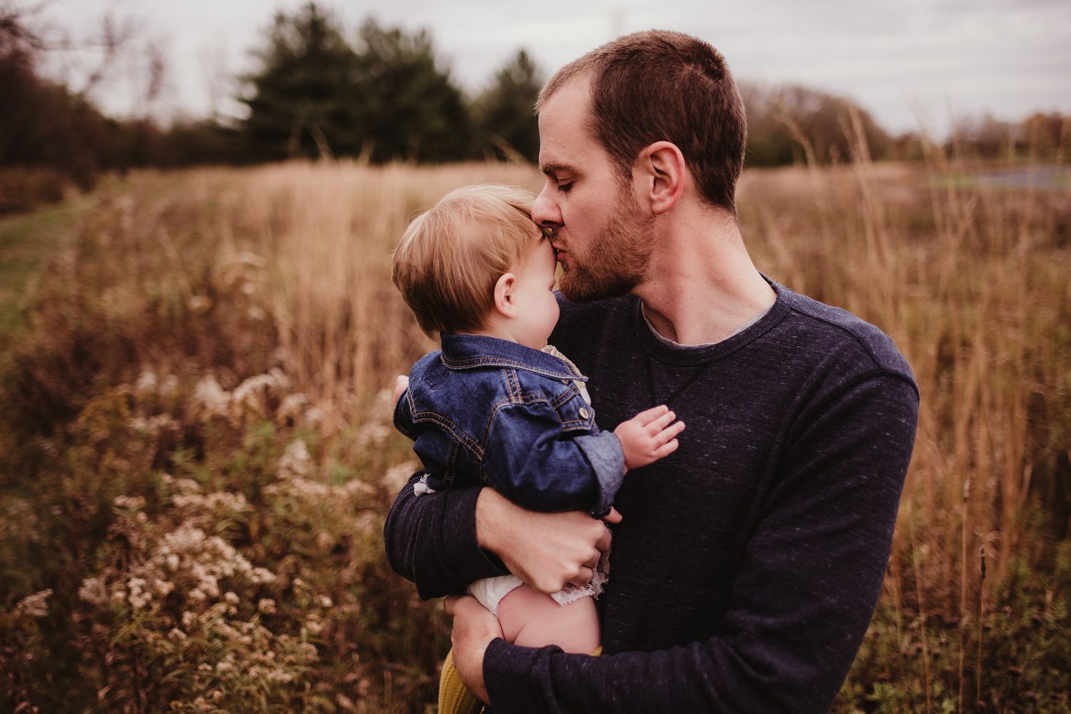 A tender moment between two people captured against natural autumn foliage.