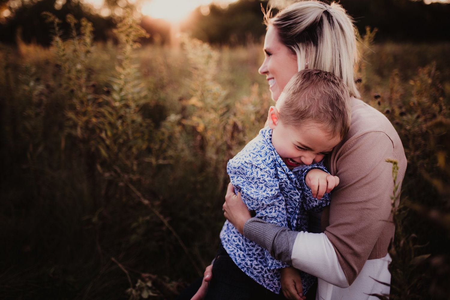 Warm embrace between adult and child in field during sunset.