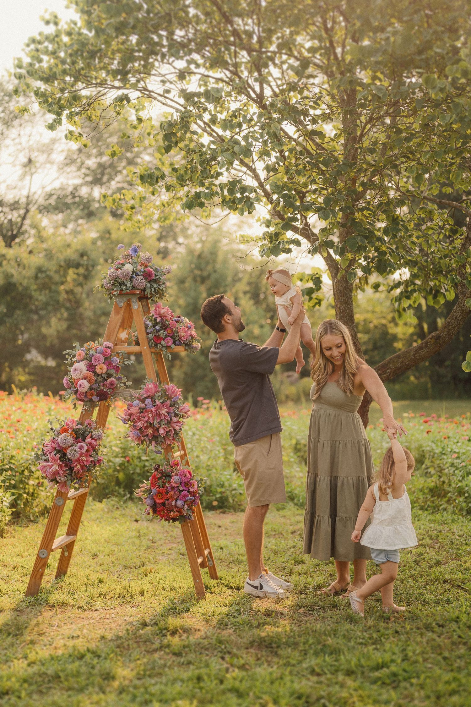 Beautiful pink and purple floral arrangement adorns a rustic wooden easel in a sunlit garden setting.