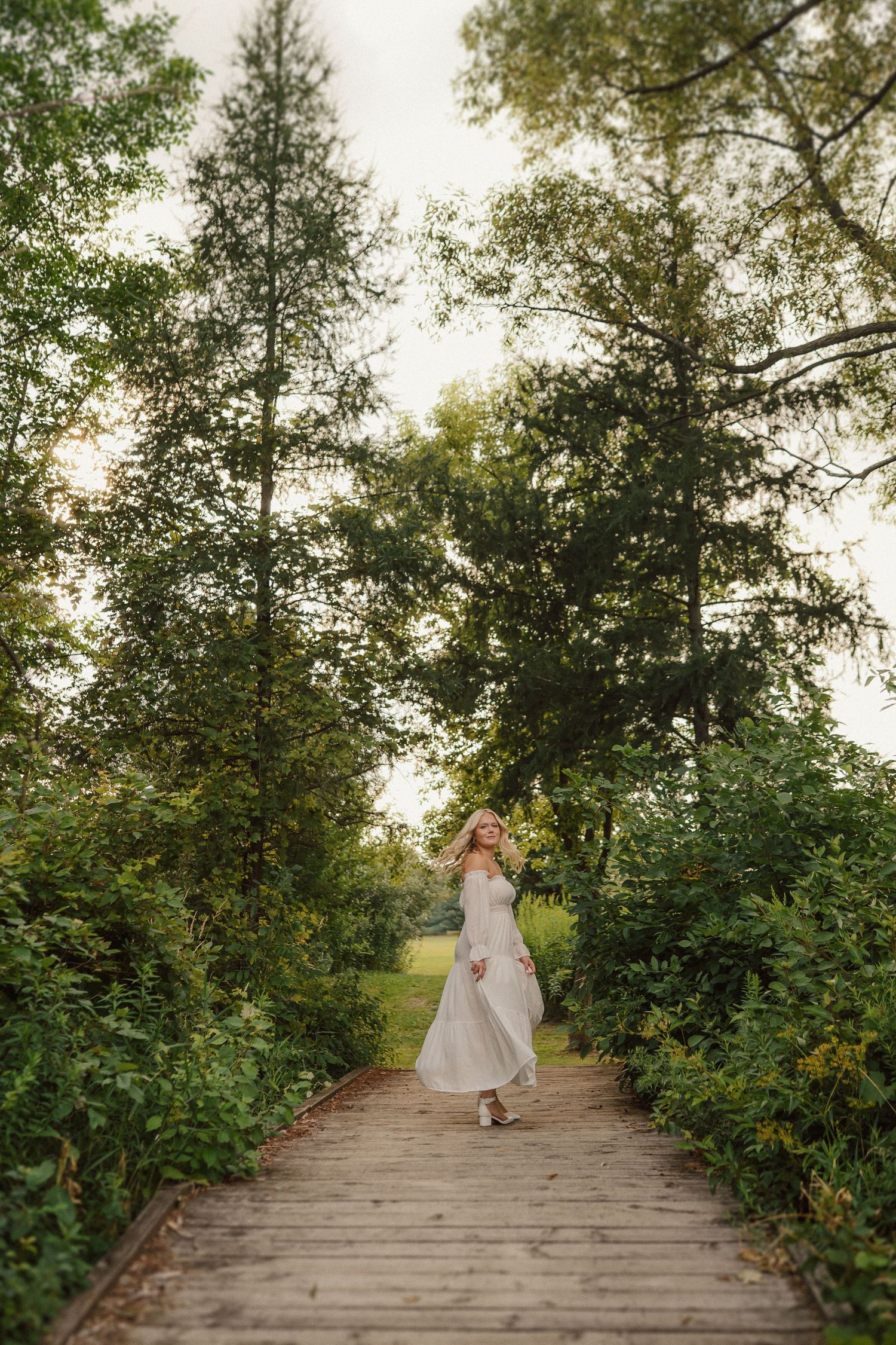 A serene boardwalk path through lush greenery and trees captured in a sequence of walking shots.