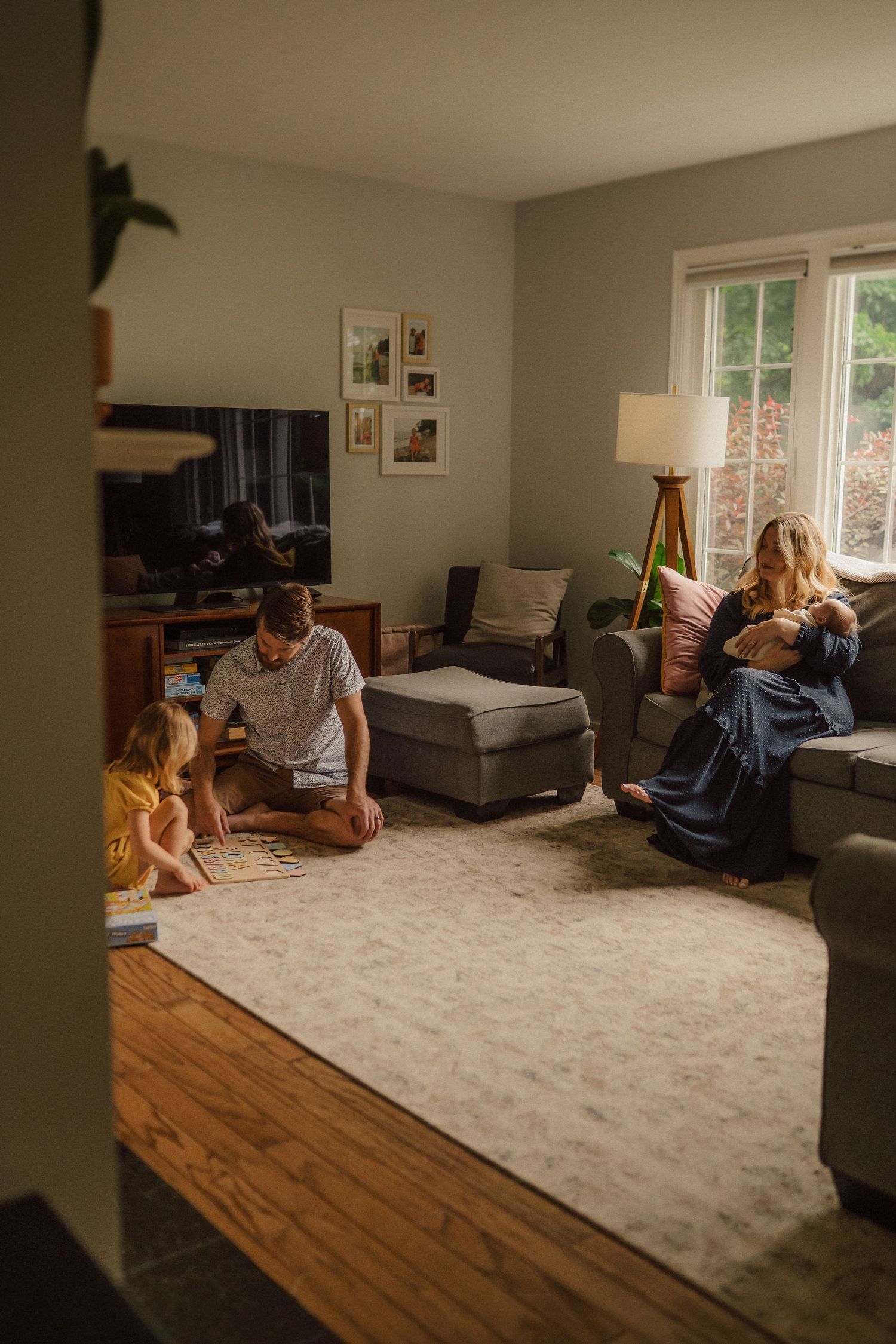 A relaxed family scene in a comfortable living room with hardwood floors and natural light.