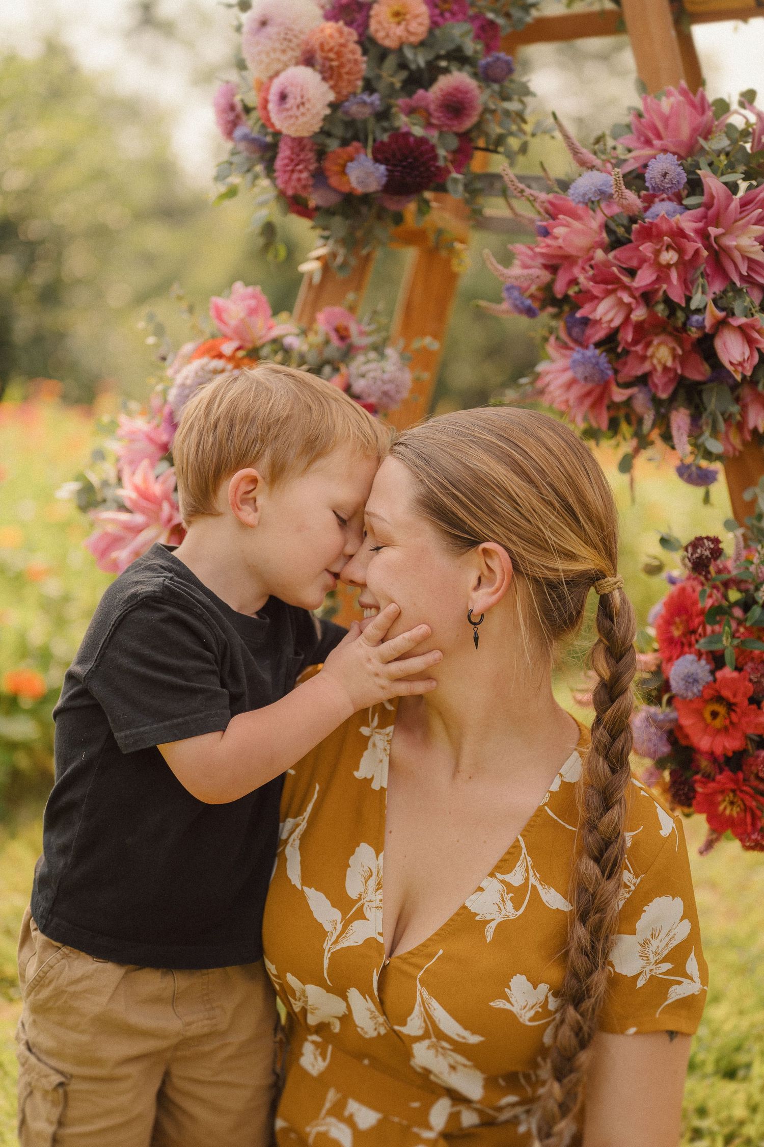 Tender moment captured outdoors with floral decor and warm sunset lighting.