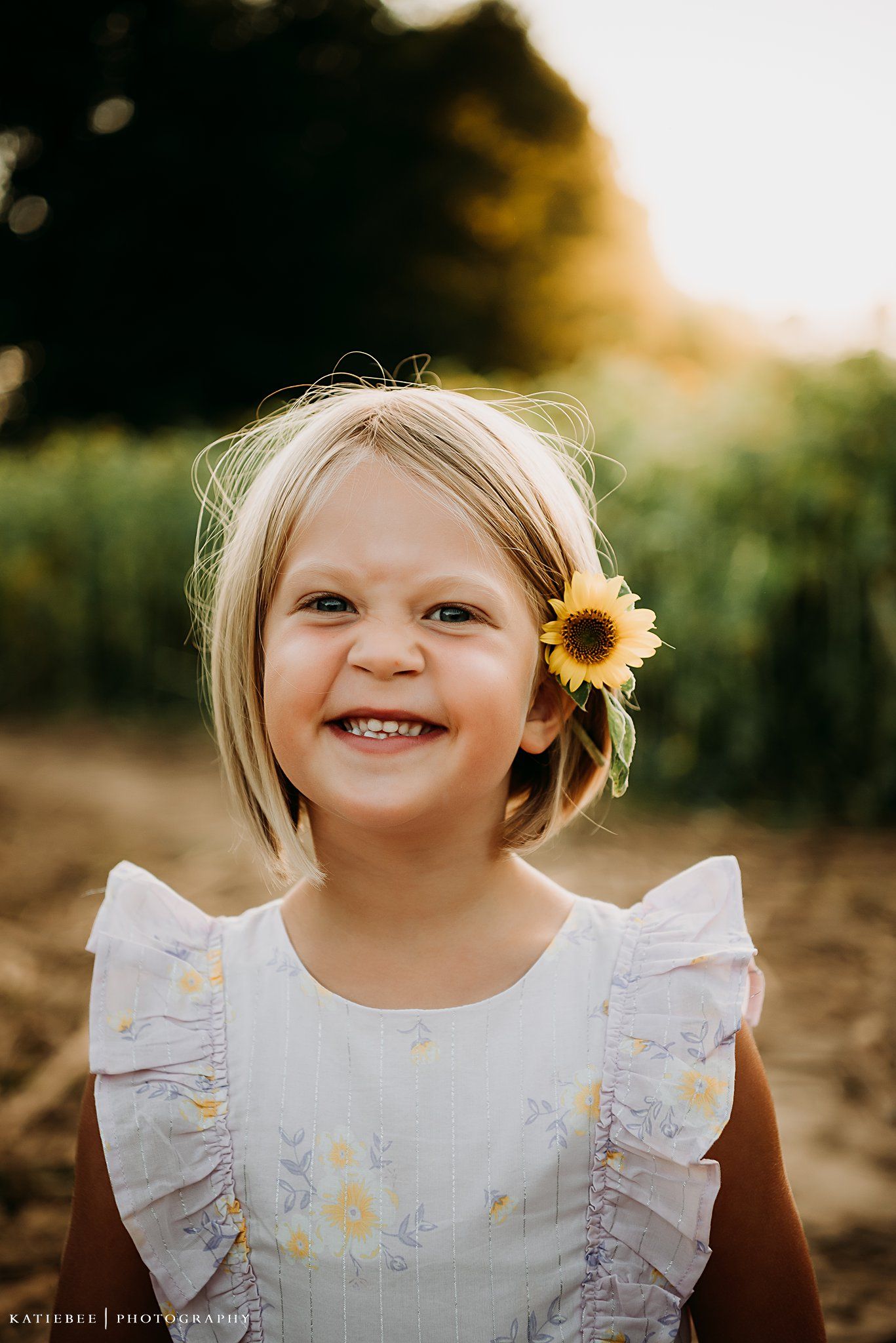 Joyful summer portrait with sunflower accent against golden evening light.