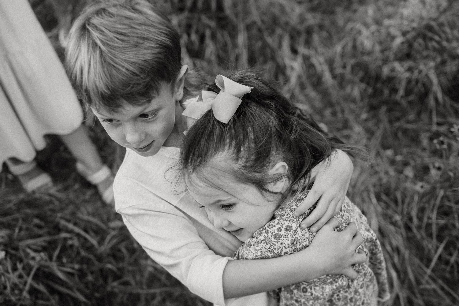 Two children share a sweet embrace in black and white photography.