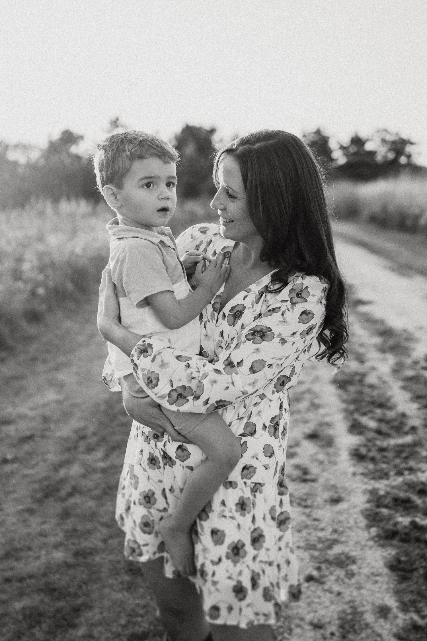 Black and white portrait of parent and child sharing an intimate moment on a country path.