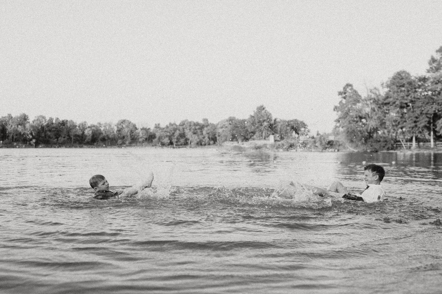 Black and white photograph of people swimming and splashing in a lake.