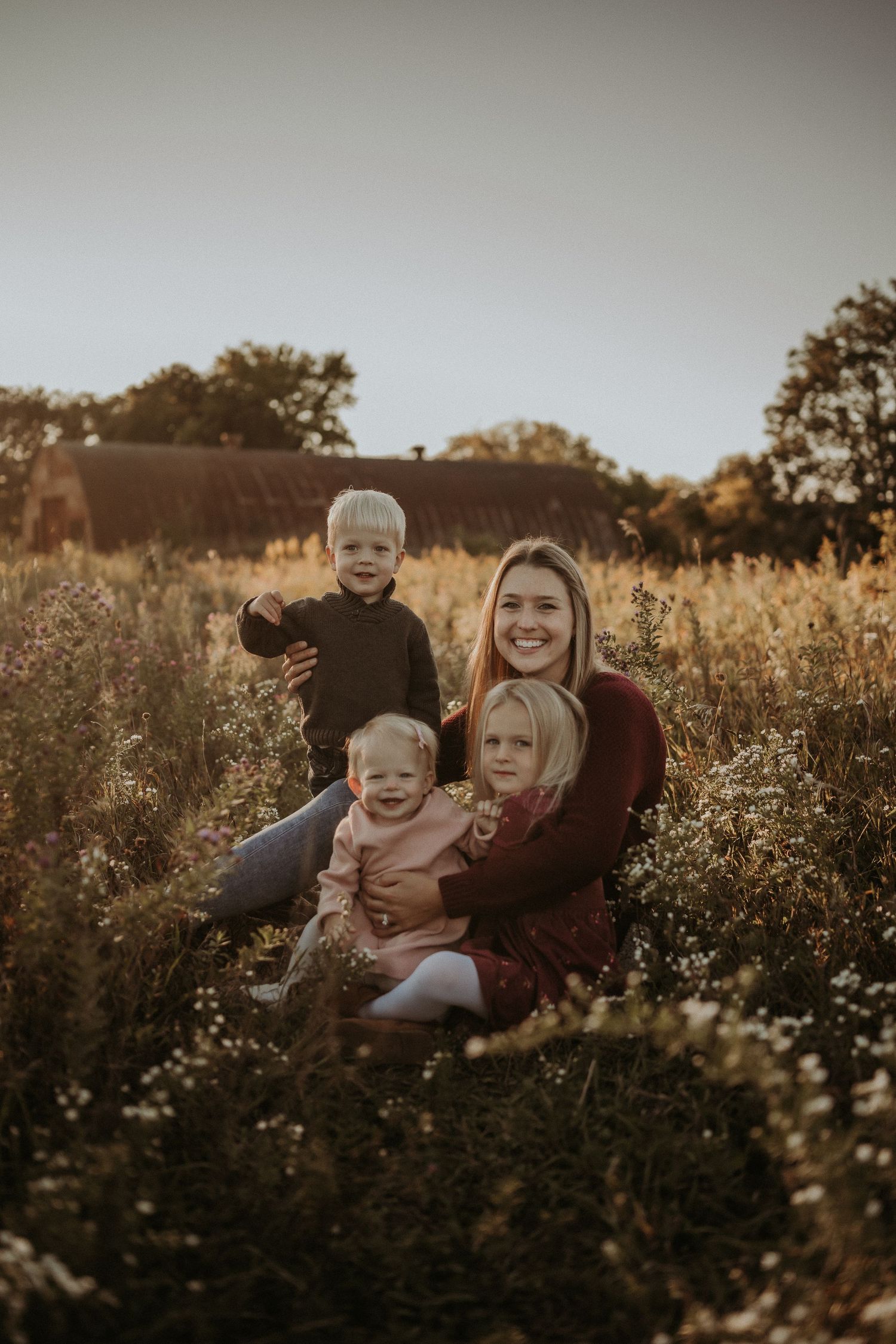 Group sitting together in a tall grass meadow at sunset.