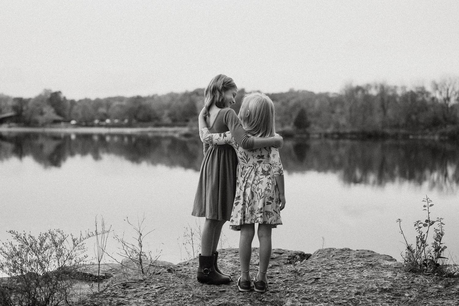 Black and white portrait of people standing along a lakeside during a fall photography session.