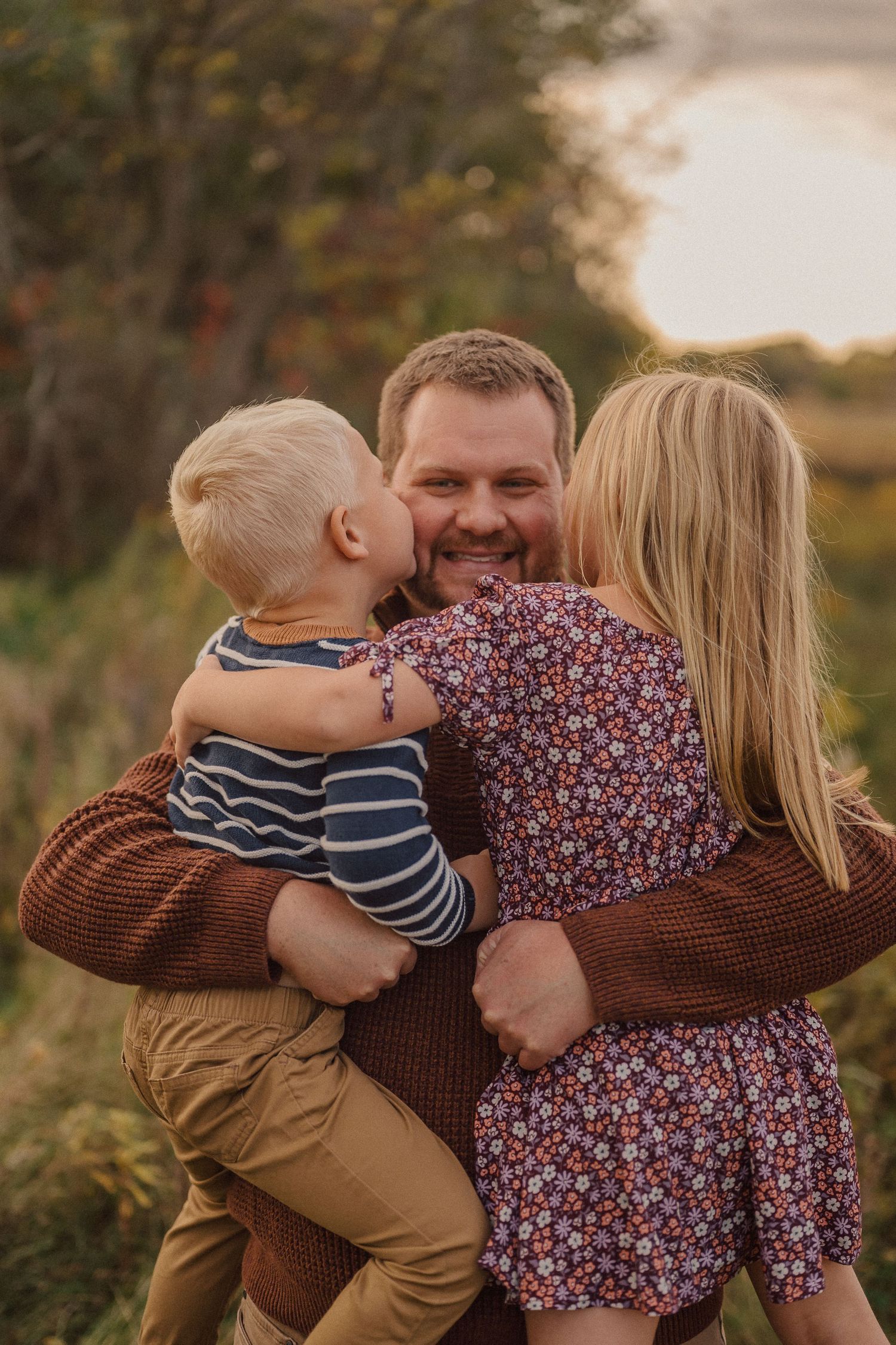Loving family embrace captured during sunset in a golden meadow.
