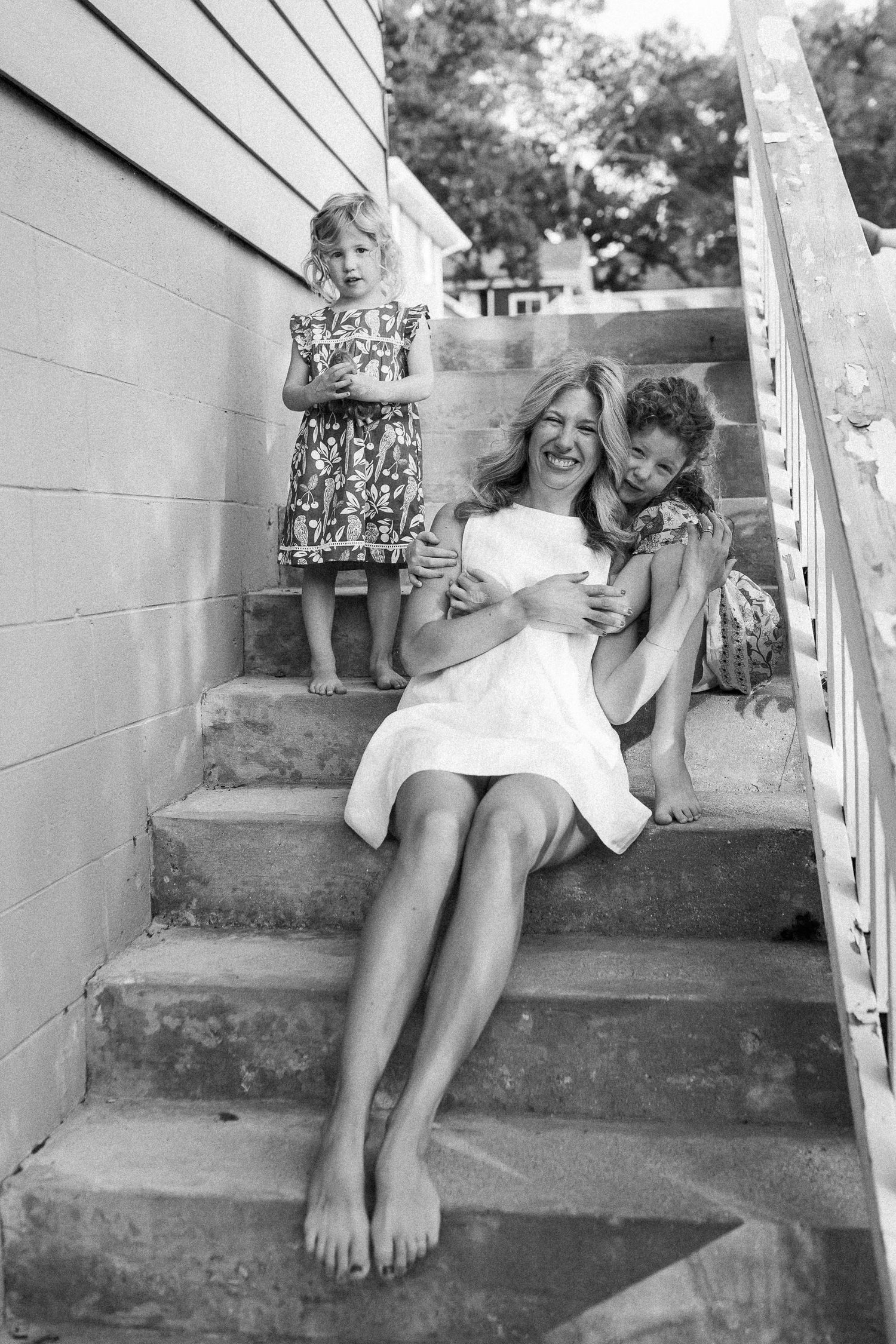 Two children sitting and laughing together on outdoor concrete steps in black and white.
