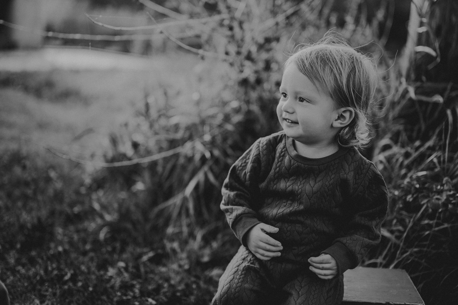 A monochrome portrait of a small child in dark clothing looking thoughtfully to the side.