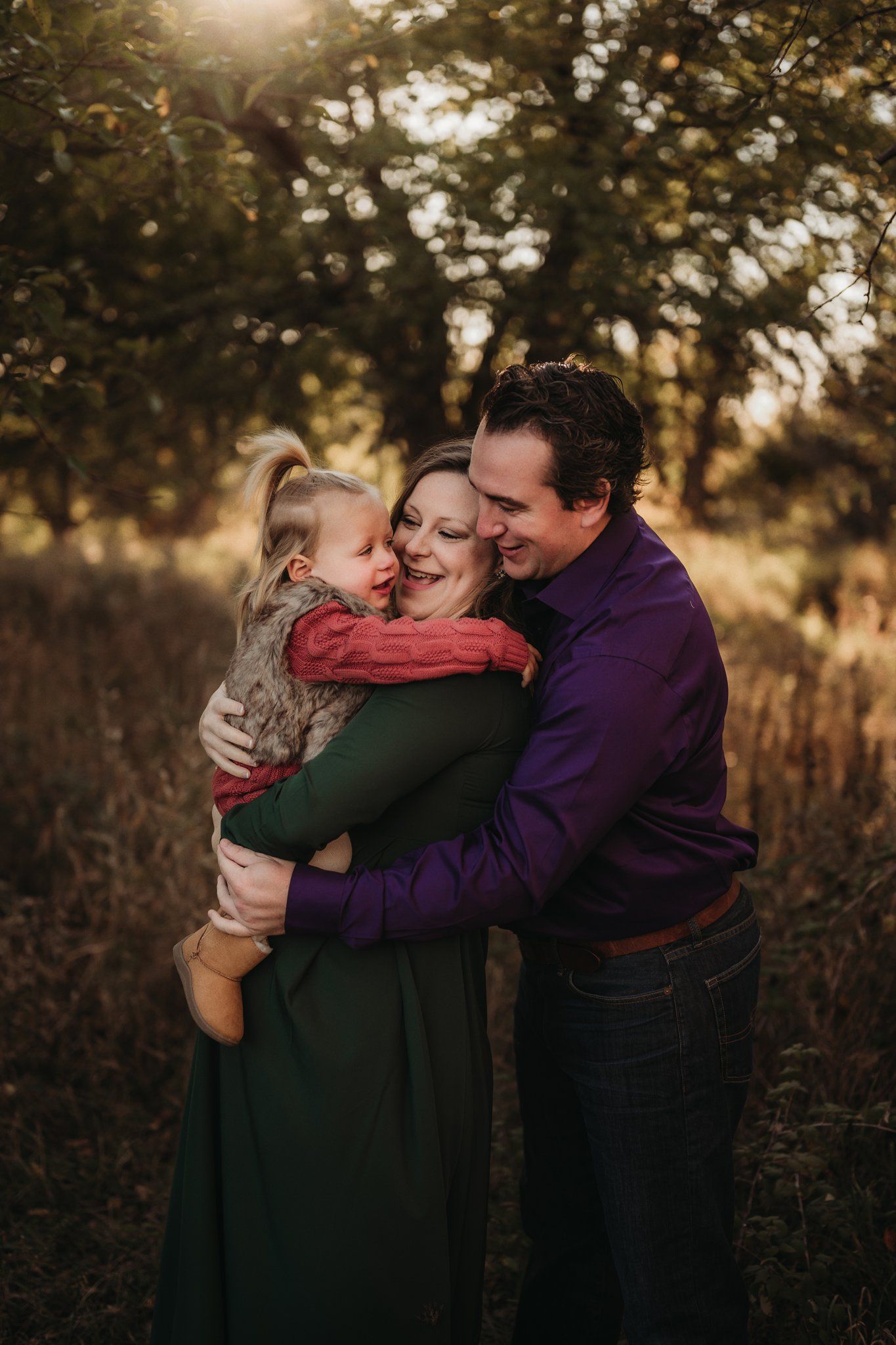 Intimate family moment captured in golden light among autumn foliage.