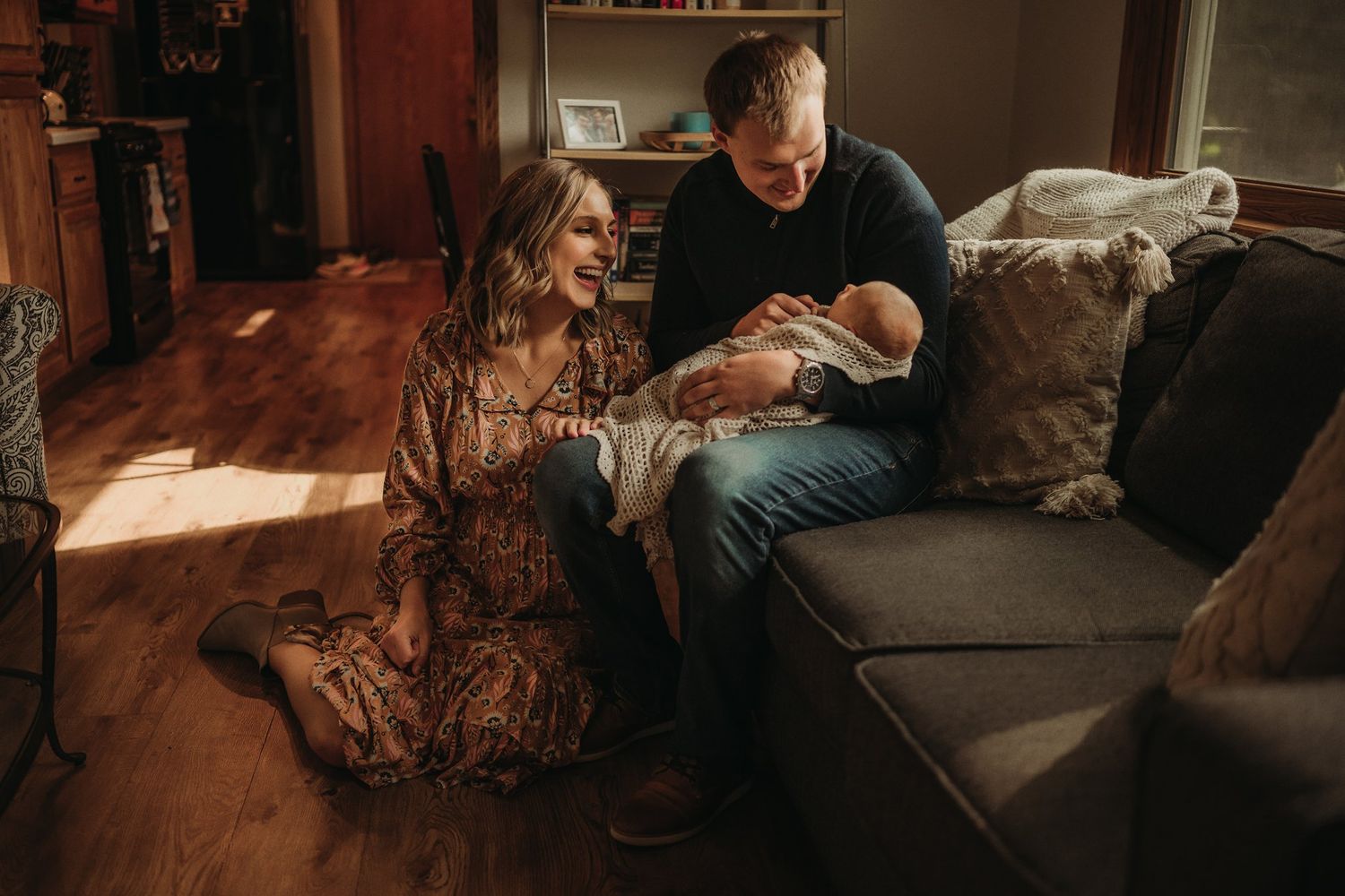 An intimate family moment on a couch with a newborn baby in warm lighting.