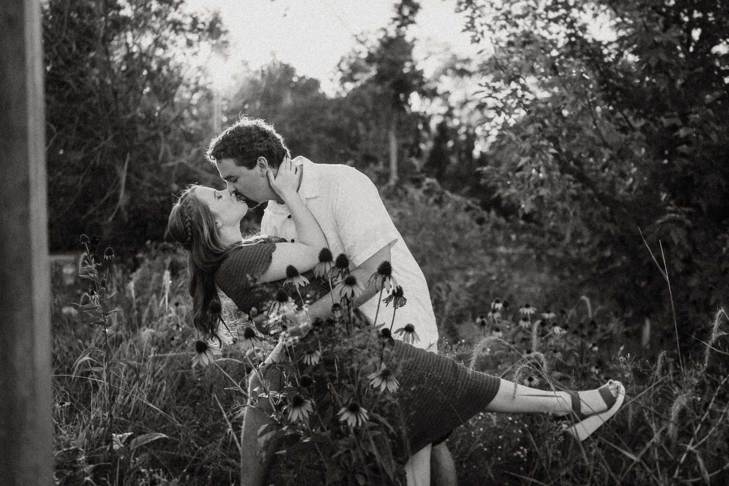 Romantic dip kiss between couple in a wildflower field.