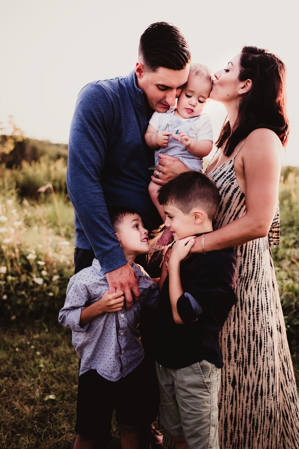 Intimate family moment captured in golden hour lighting with everyone huddled close together.