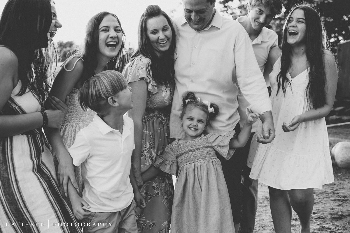 A black and white photo of a group laughing together by the water.