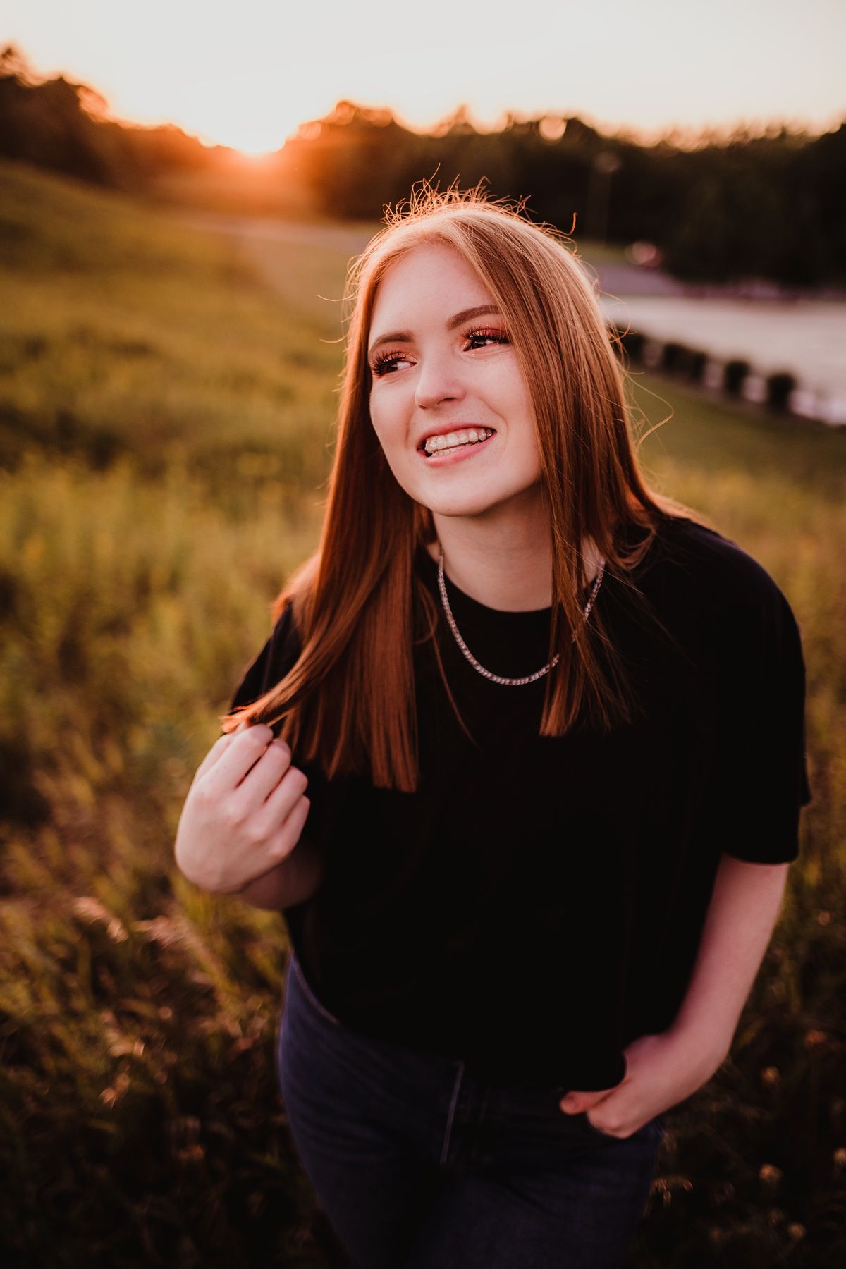 Portrait of a person in black top during golden hour sunset with glowing background.