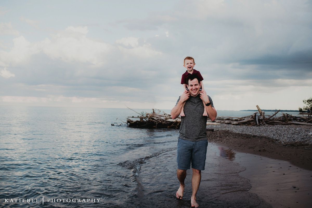 Playful moment captured on beach with cloudy sky and calm water in background.
