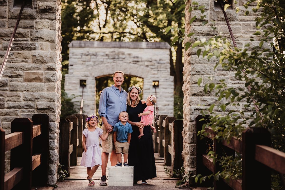 Family walks through a stone archway together during an outdoor photo session.