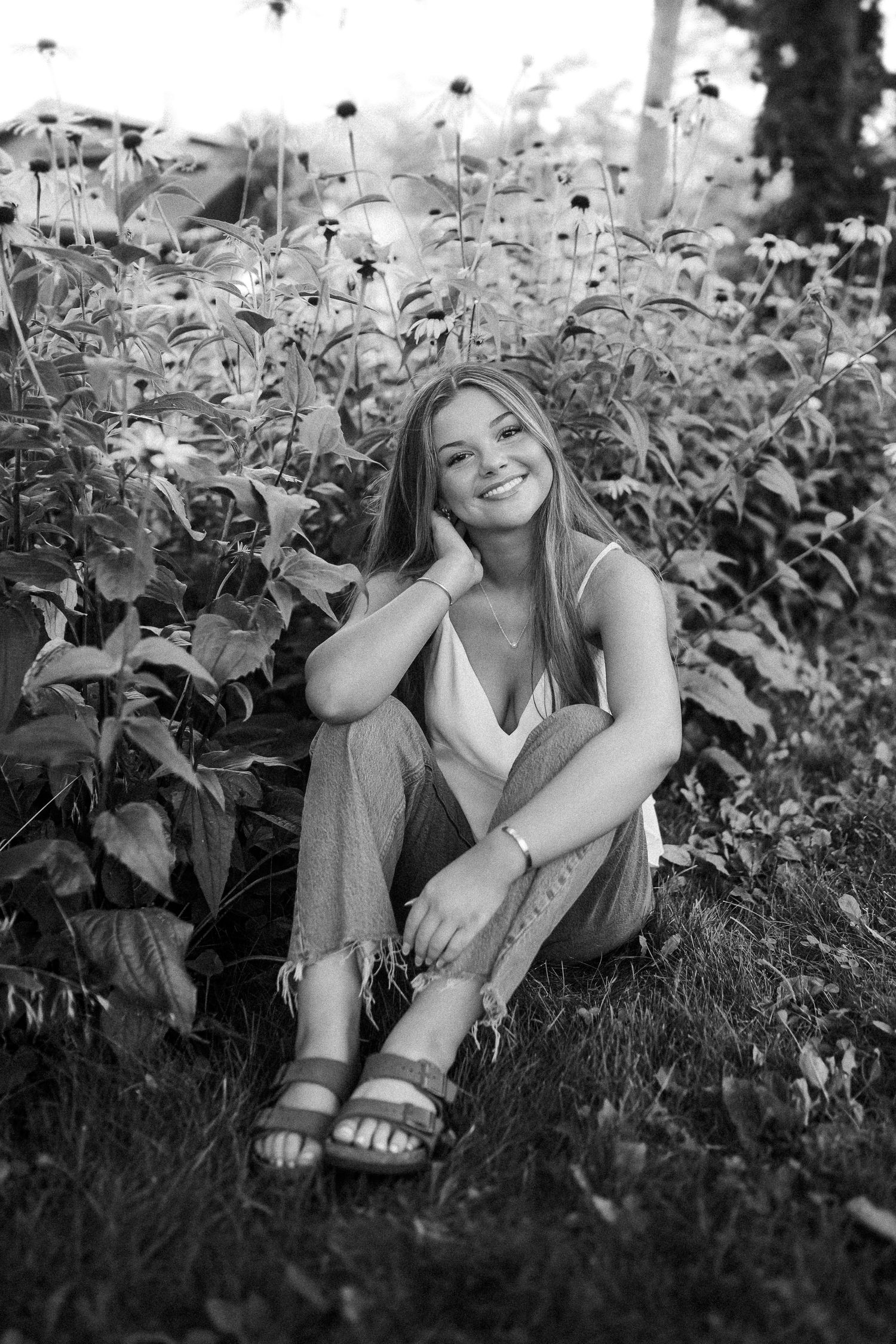 Black and white portrait taken among tall wildflowers and plants in a natural setting.