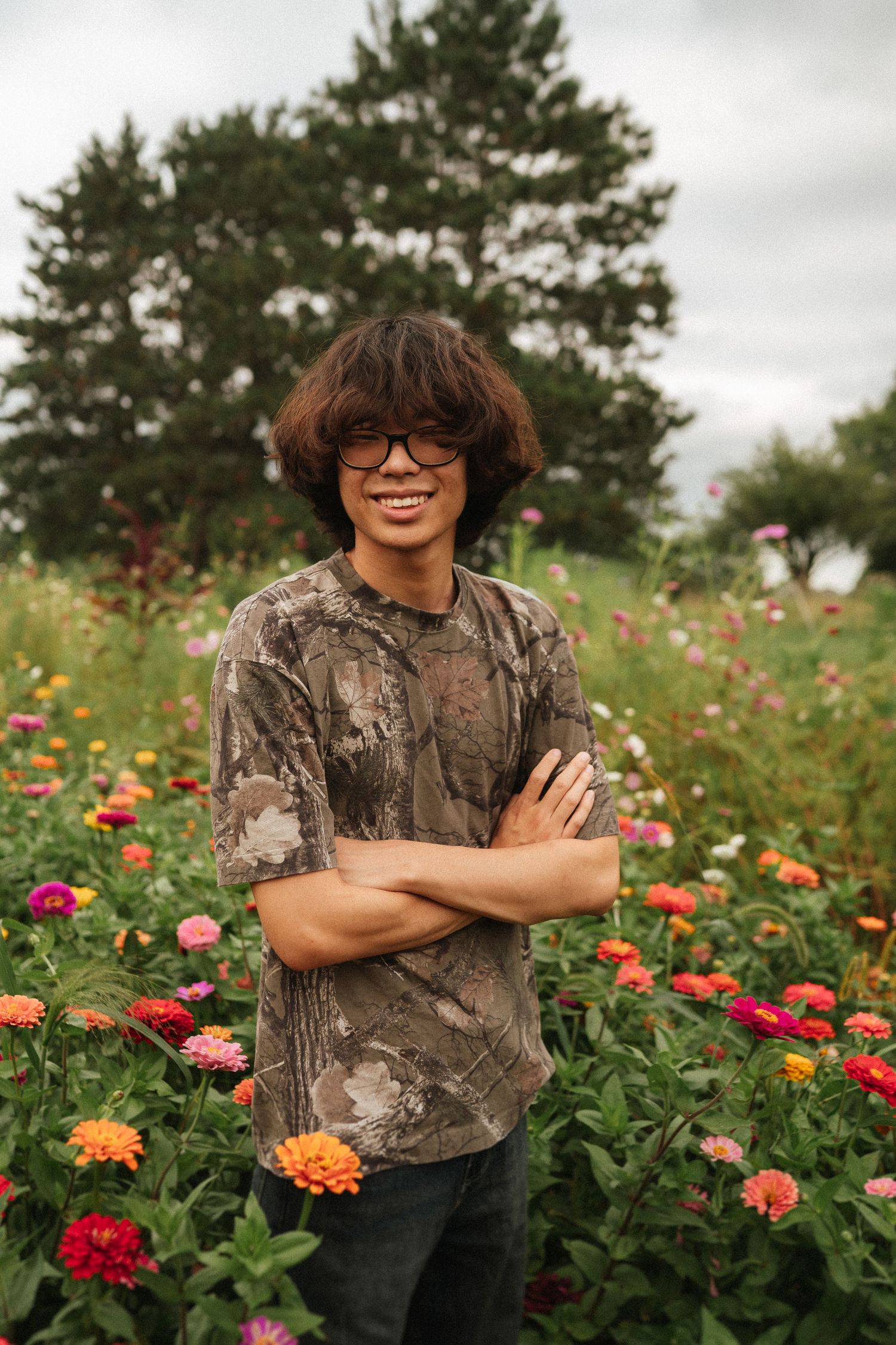 Multiple photos showing a person wearing glasses amidst a vibrant wildflower garden filled with red, orange and pink blooms.