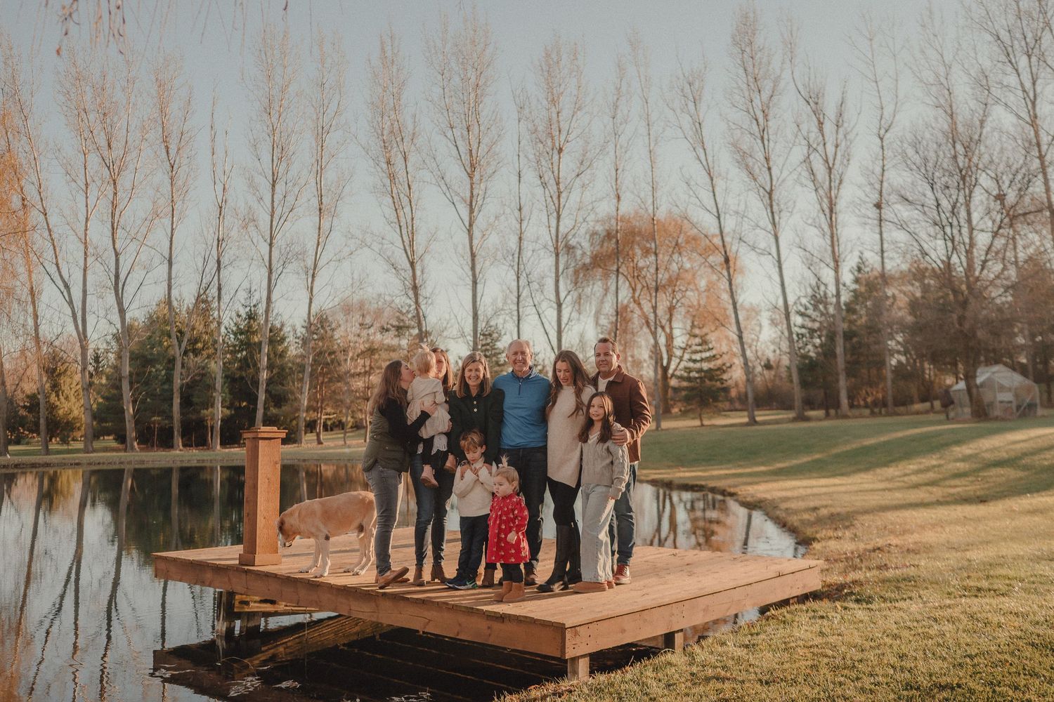 Group gathered on a wooden deck platform overlooking a scenic autumn landscape at sunset.