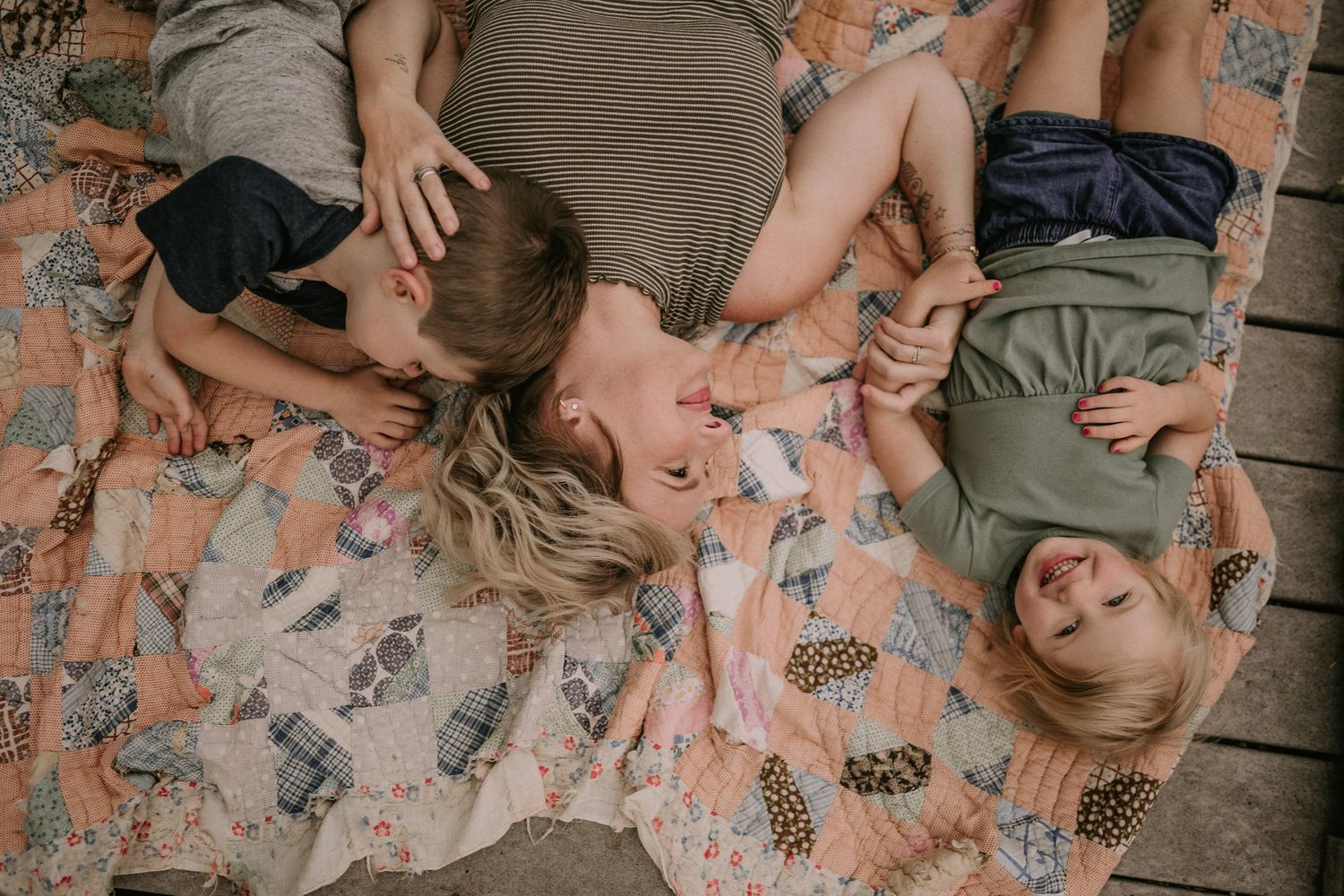 Family laying together on a floral patterned rug while playing and laughing.