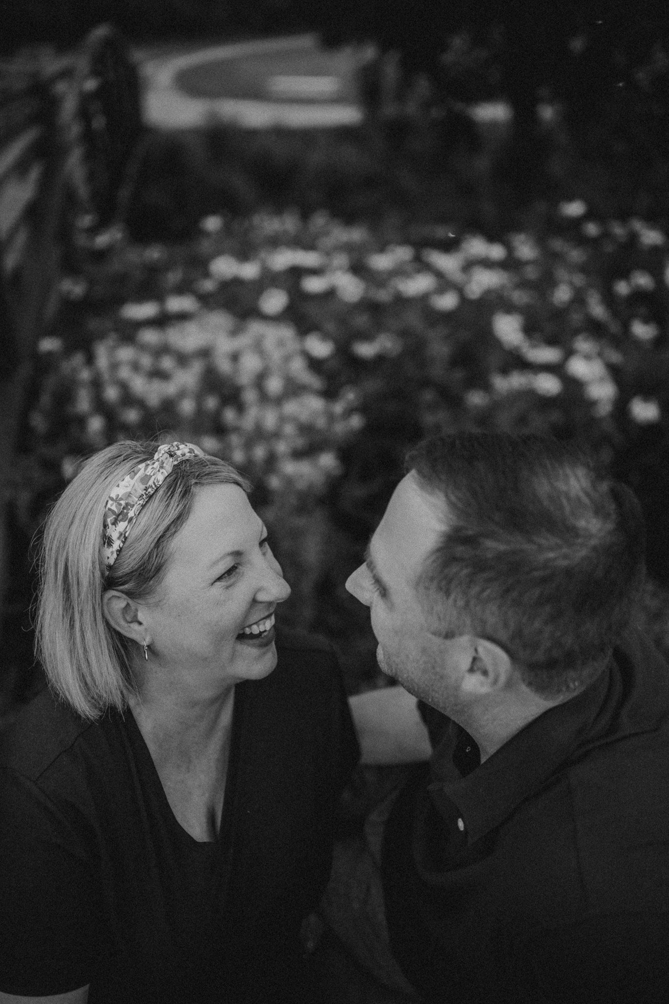 A candid black and white photo capturing laughter and connection in a garden setting.