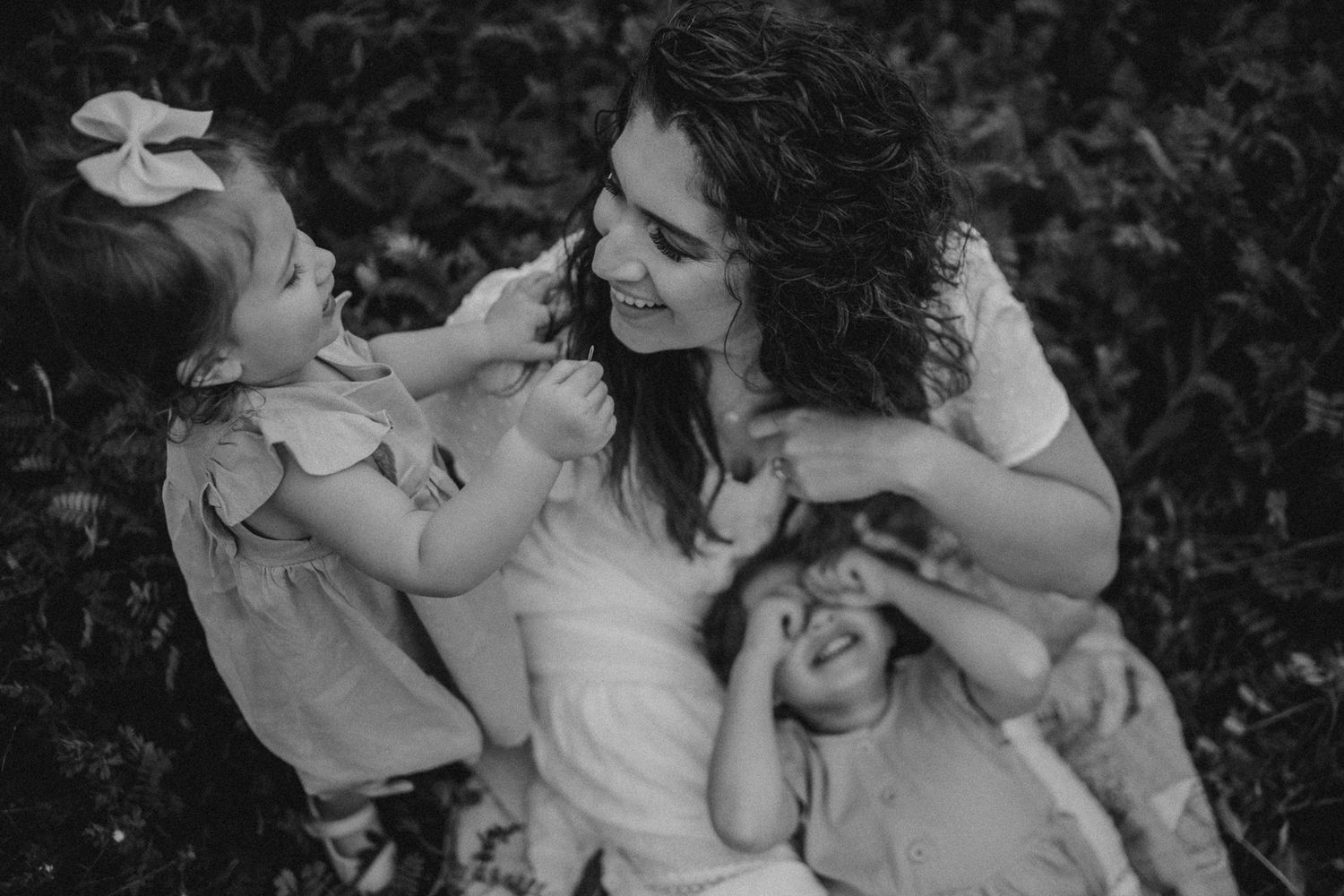 A joyful black and white candid moment shared between family members in a garden setting.