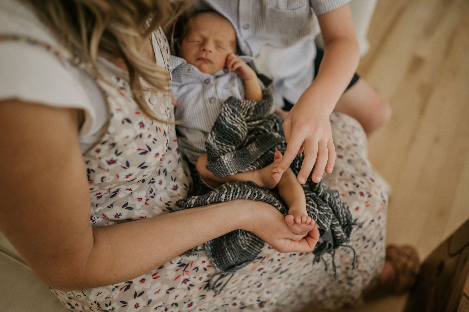 Close-up view of hands holding a sleeping newborn baby wearing striped clothing.