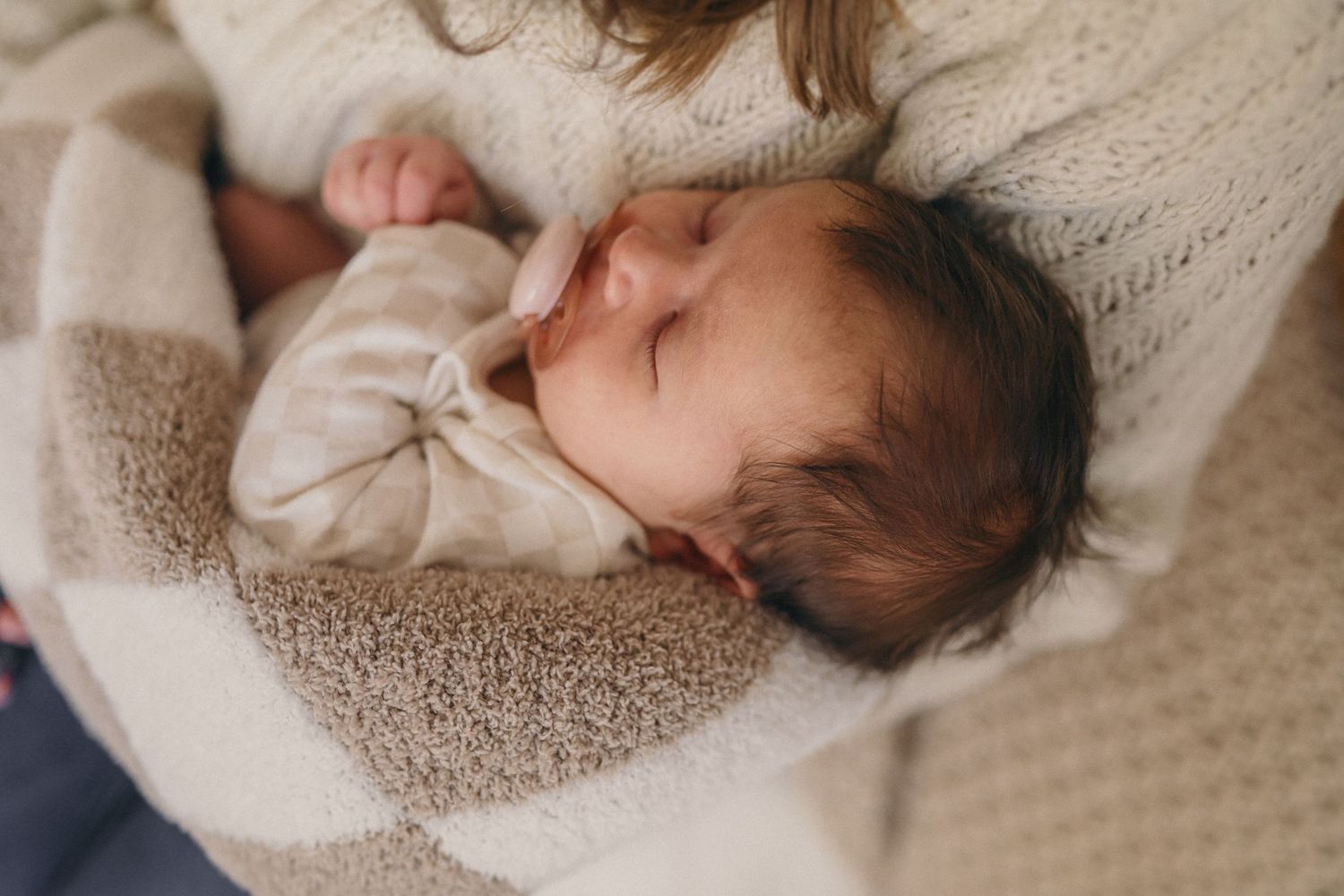A sleeping baby wrapped in warm knit blankets, lying peacefully on a cozy bedding.