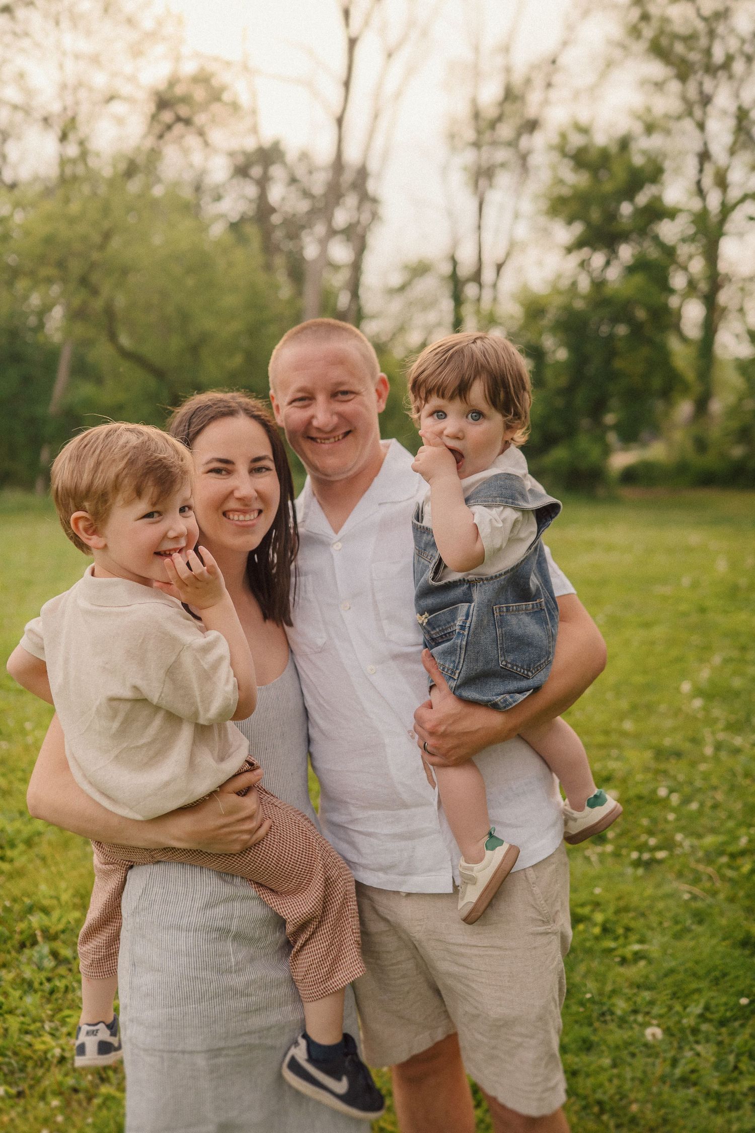Happy family of four spending time together outdoors in a grassy field on a spring afternoon.