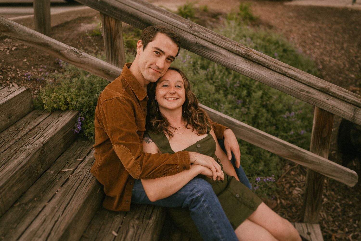A couple relaxes on rustic wooden steps during golden hour.