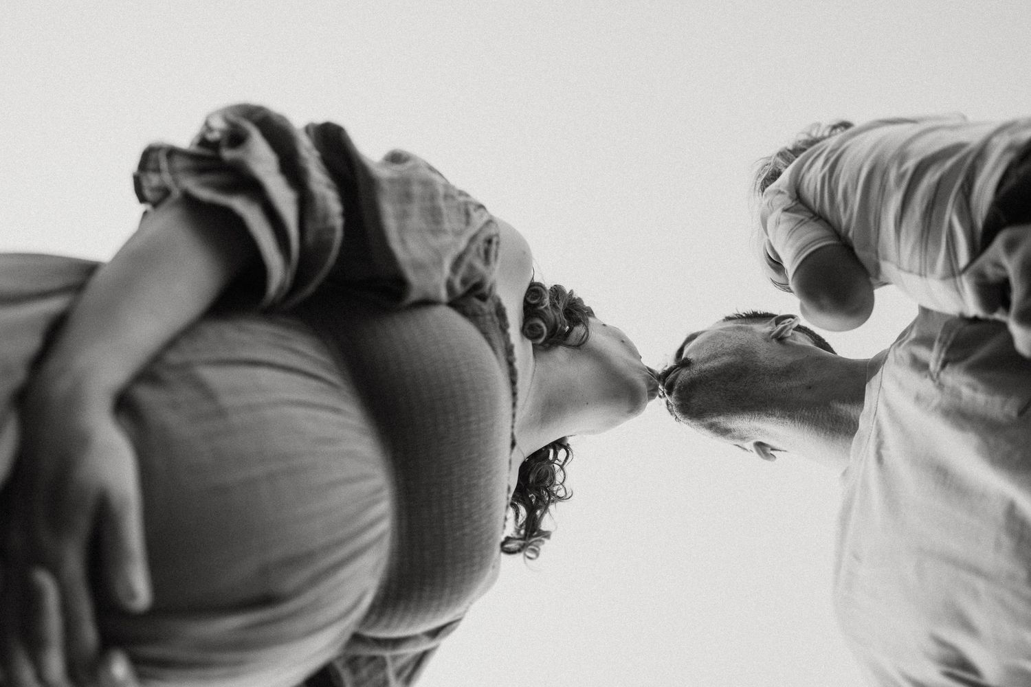 Black and white low-angle portrait of three people looking down at the camera.