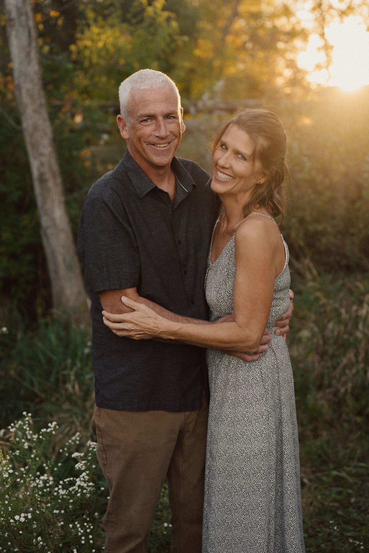 Couple shares intimate moments during sunset photoshoot in wooded area.