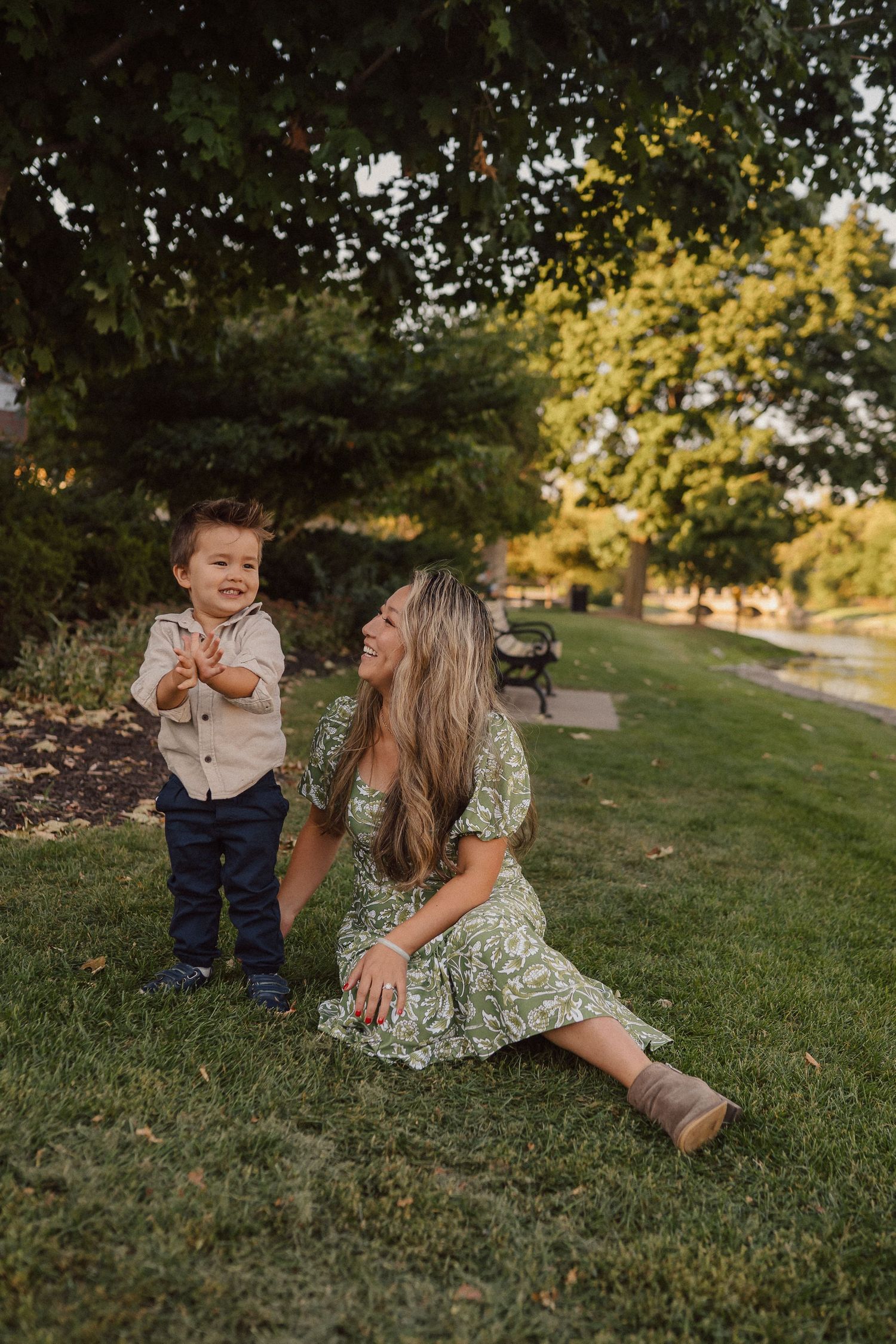 Playful interaction between parent and child on a green hillside during golden hour photography session.