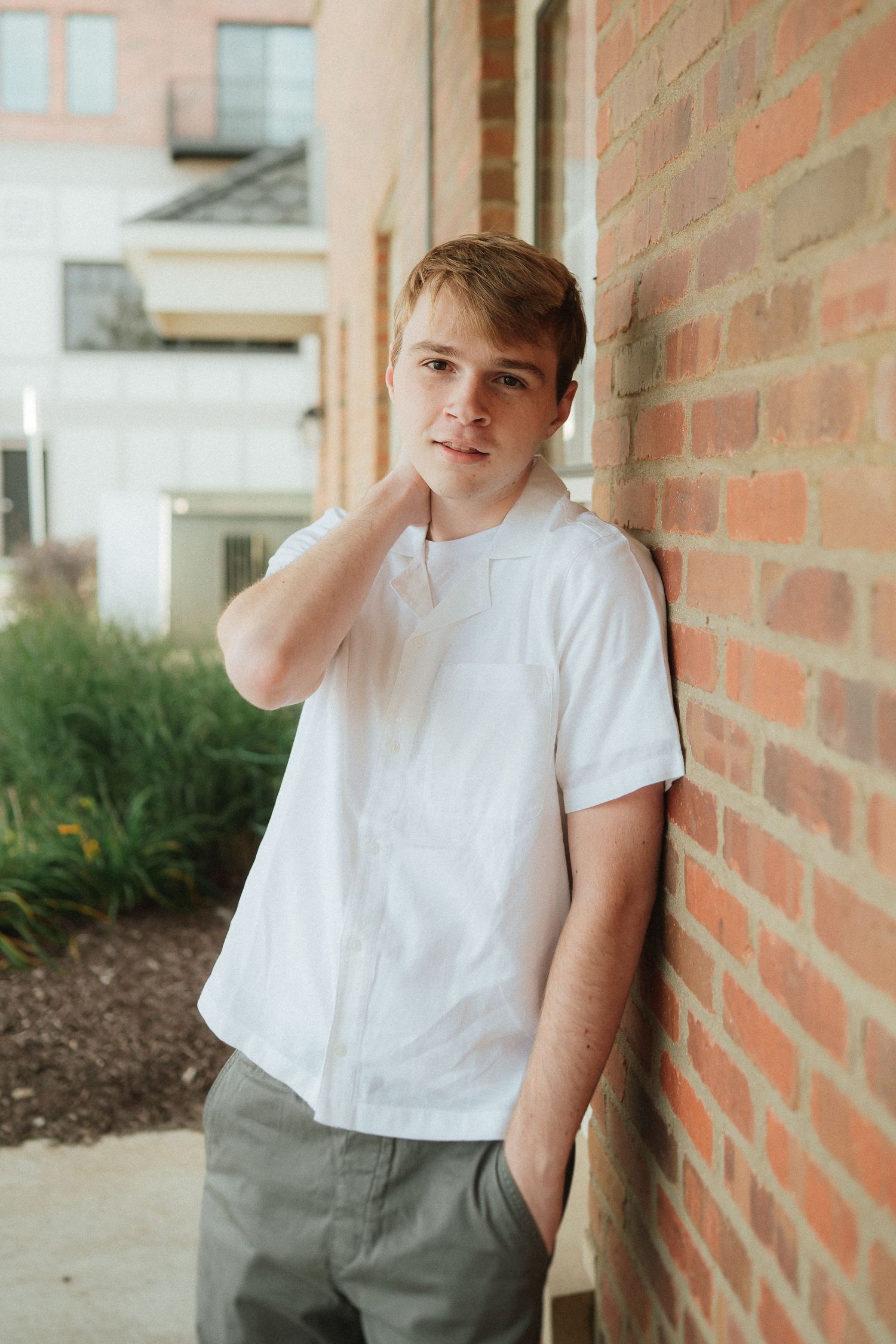 A series of casual portraits against a brick wall with natural lighting and simple white t-shirt styling.