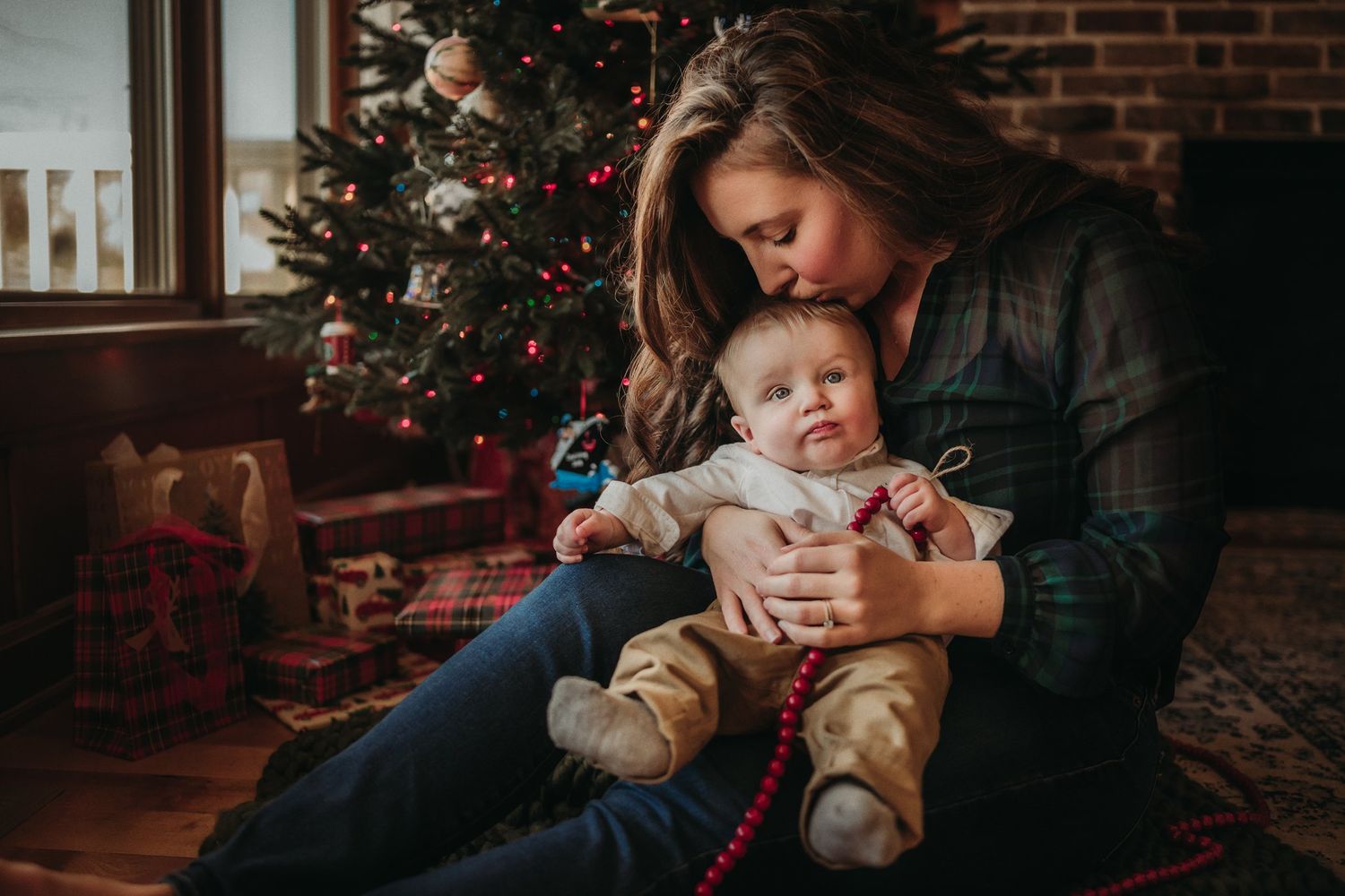 Intimate holiday scene near a Christmas tree with soft lighting and festive decorations.