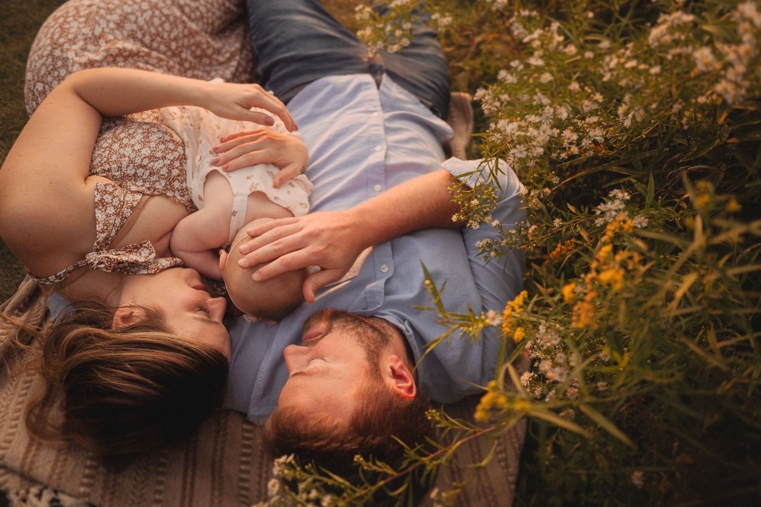 A family lying in wildflowers during golden hour creating an intimate outdoor portrait.