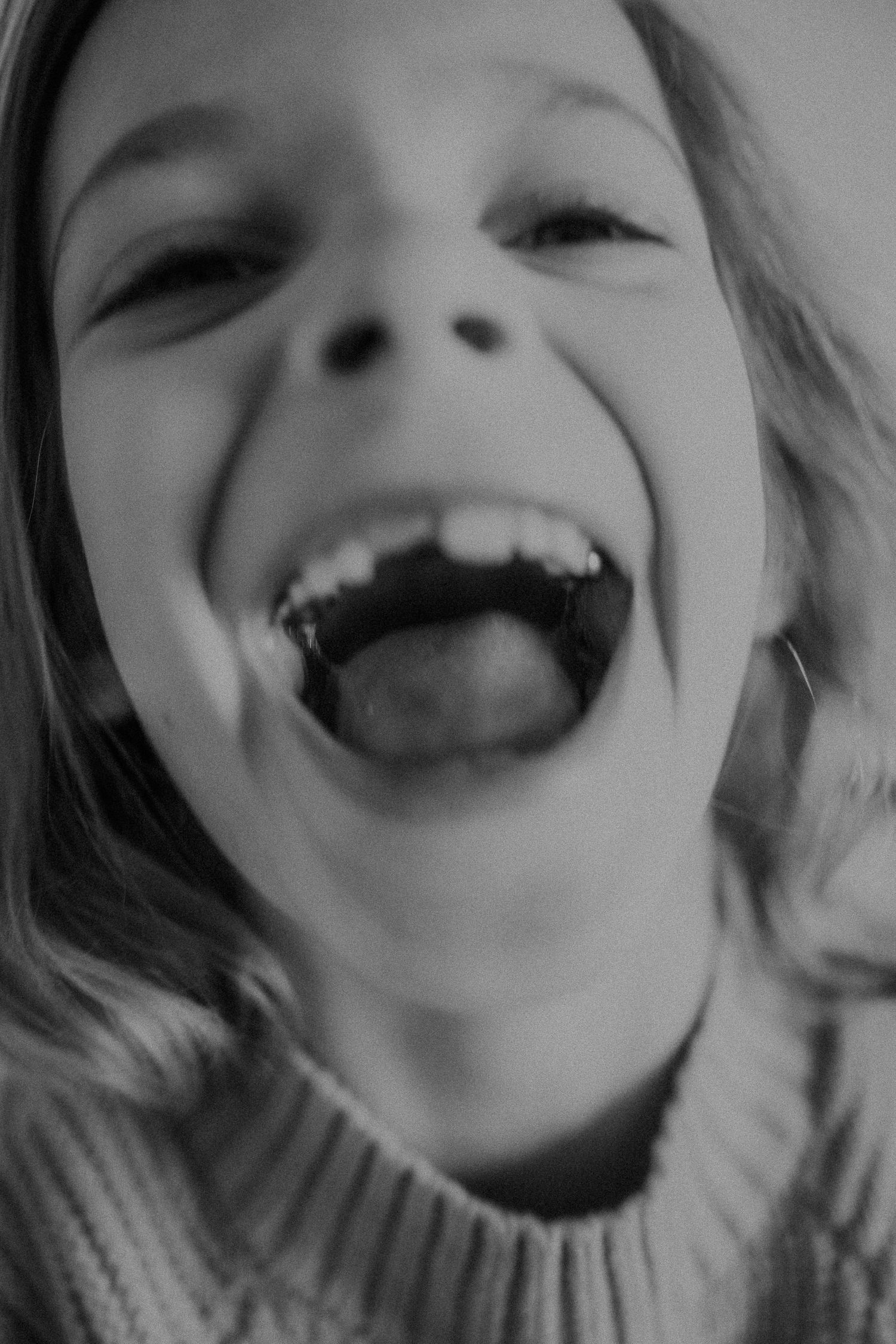 Black and white close-up portrait of joyful laughter with an open mouth.