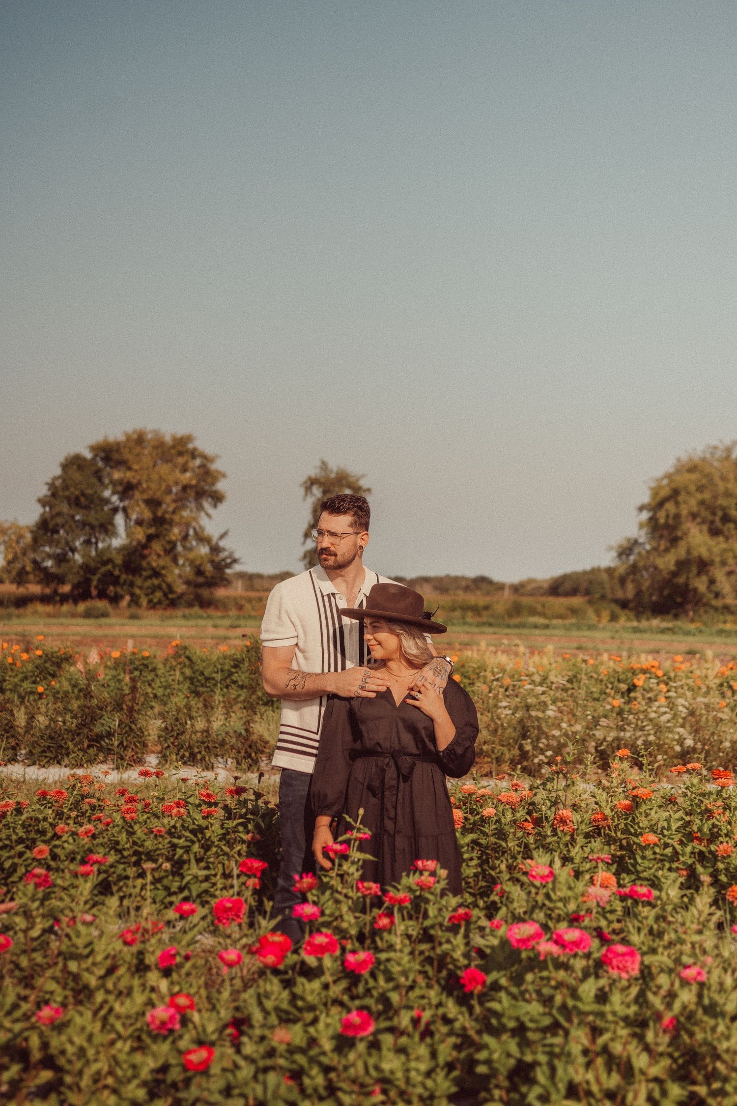 A tender moment captured between a couple among blooming red flowers at golden hour.