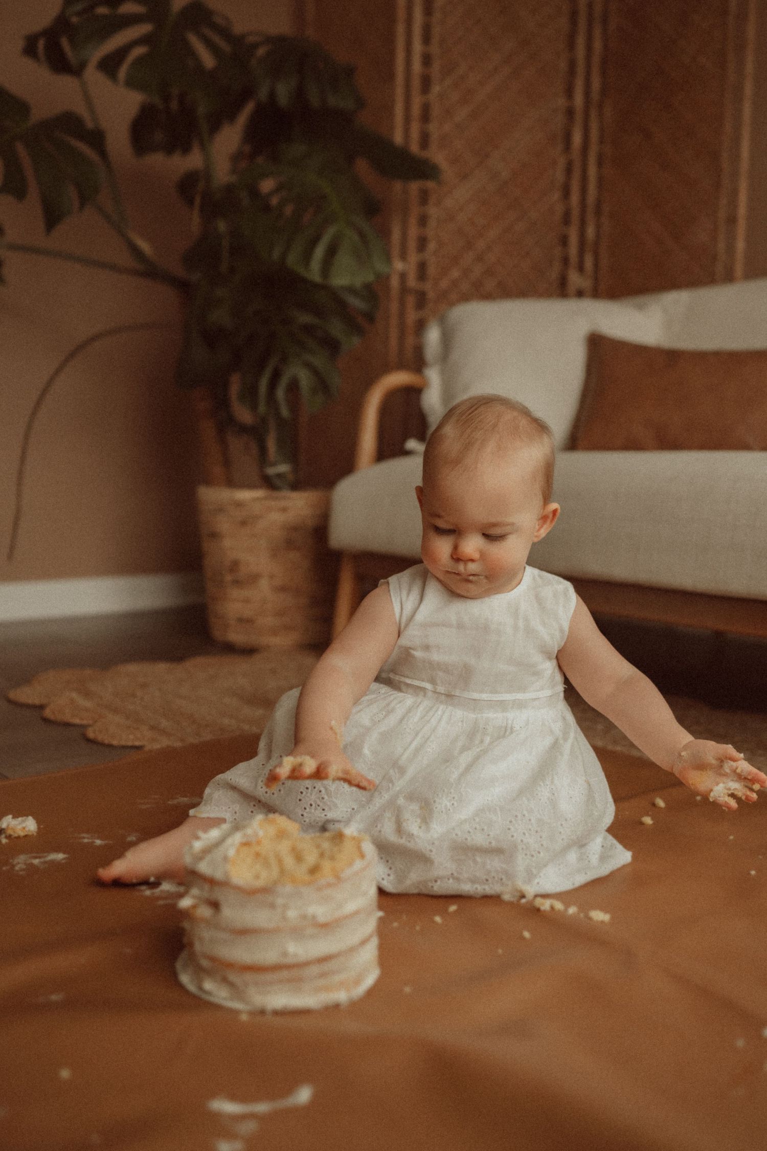 Warm-toned photo of a cake smash session showing scattered crumbs and frosting.