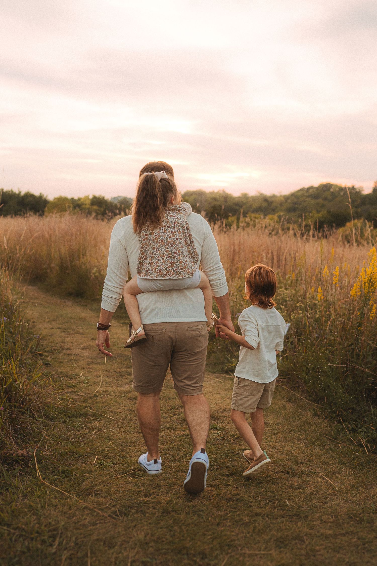 Two people walking hand in hand along a nature path during golden hour.