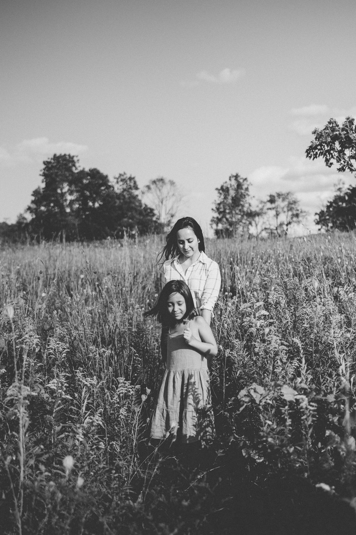 Black and white portrait of two people standing together in a wildflower field on a sunny day.
