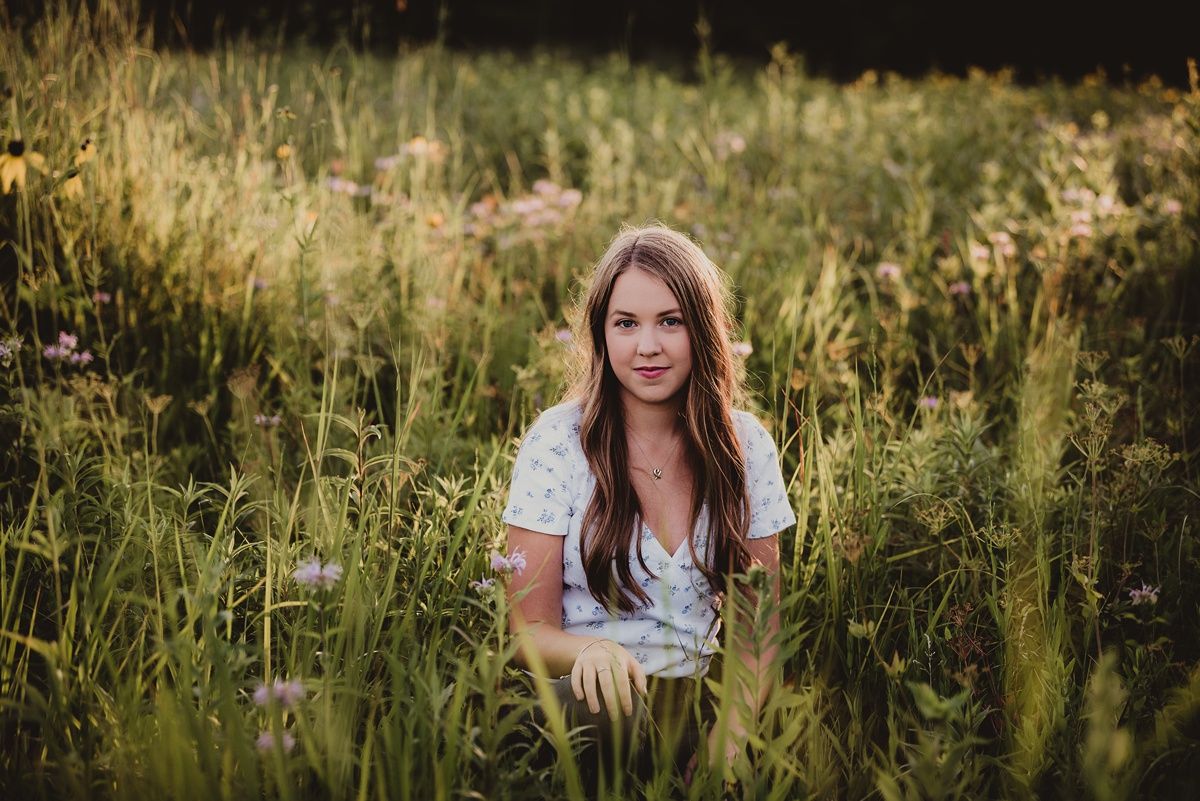 Outdoor portrait among tall grass and wildflowers during late afternoon light.